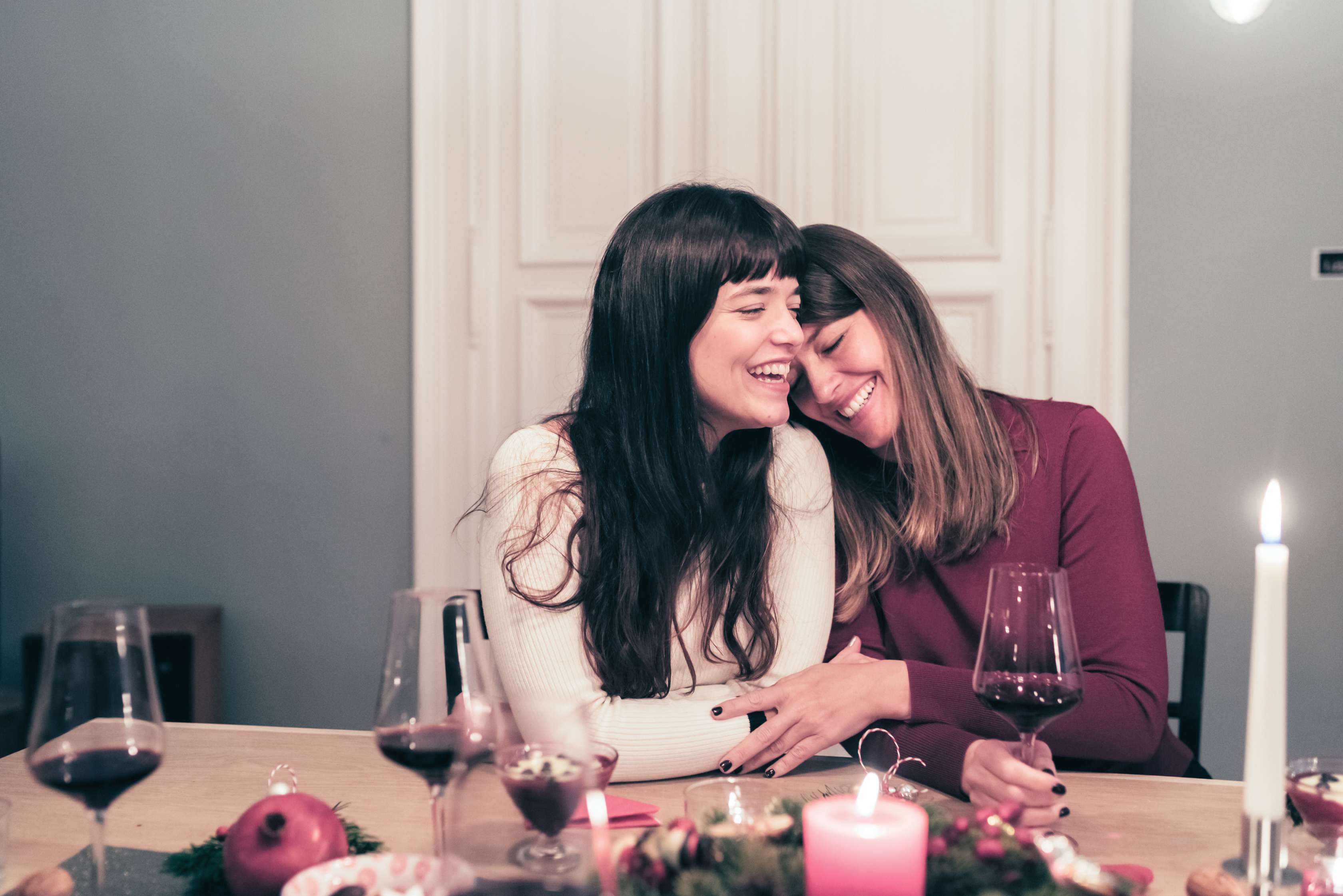 Zwei Freundinnen sitzen mit einem Glas Rotwein am Tisch