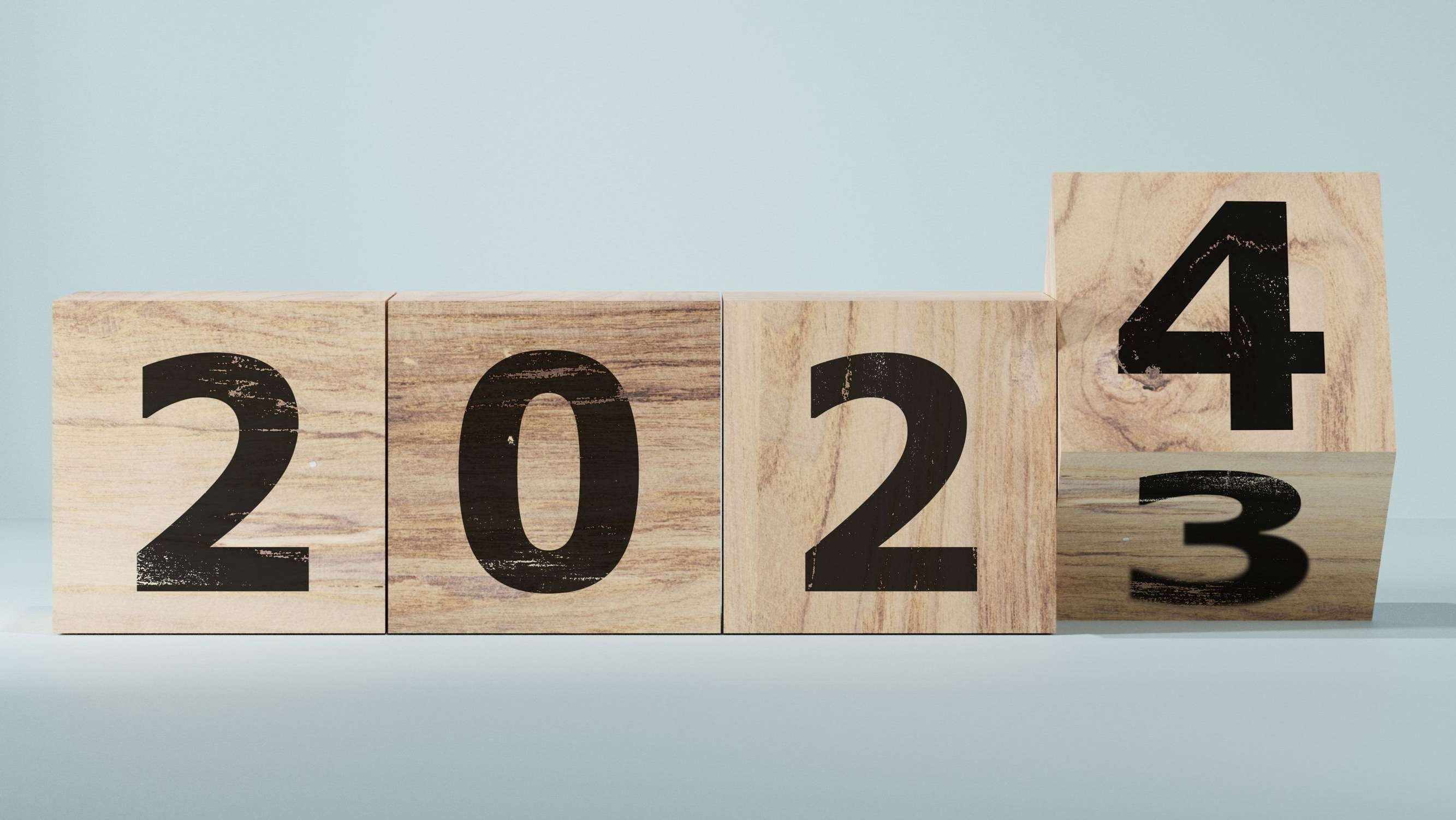 Jahreszahl 2023, bzw. 2024 auf vier Holzwürfel gedruckt, letzte Zahl dreht gerade von der 3 auf die 4.