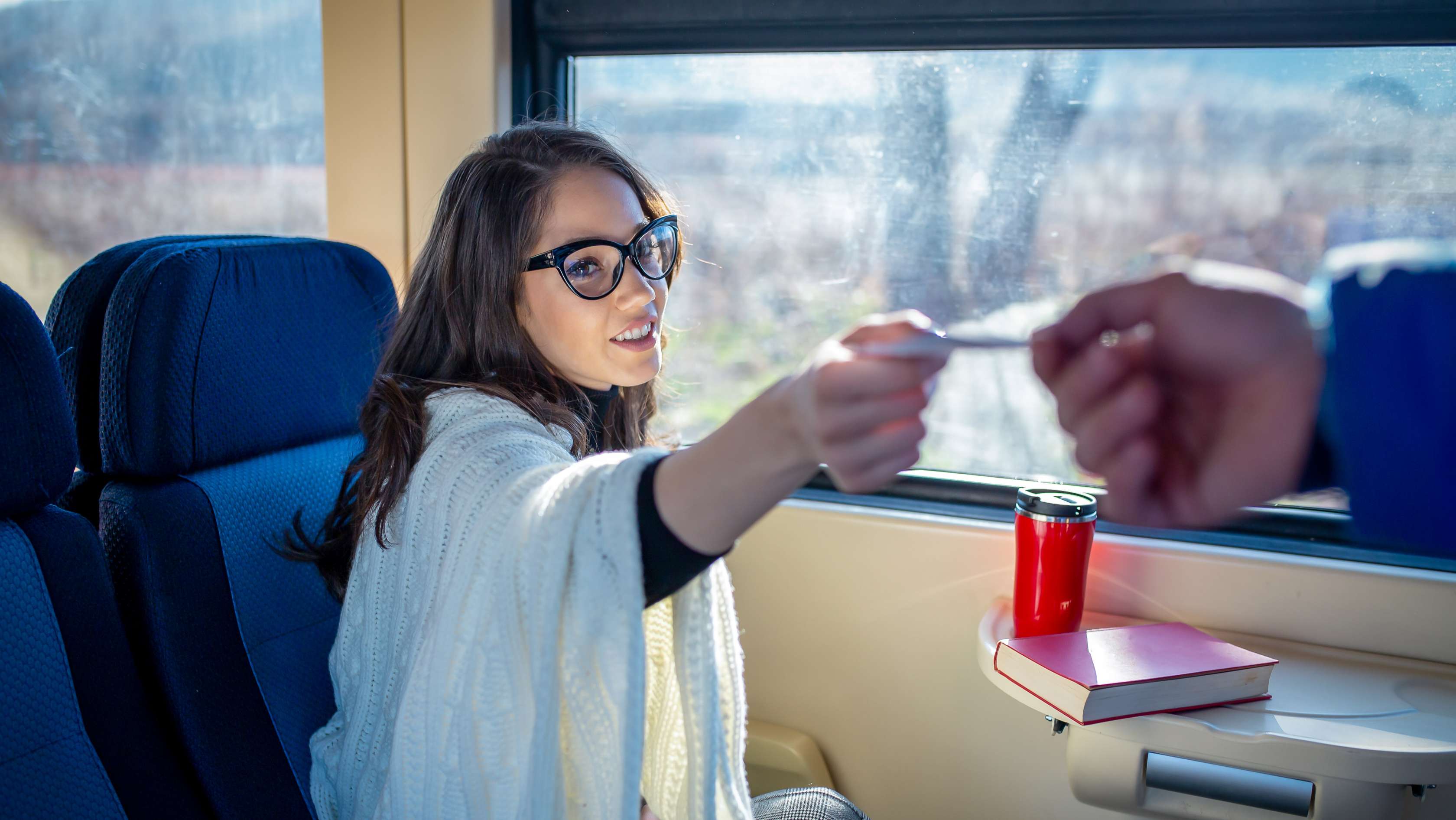 Frau in einem Zug reicht Schaffner ihre Bahncard