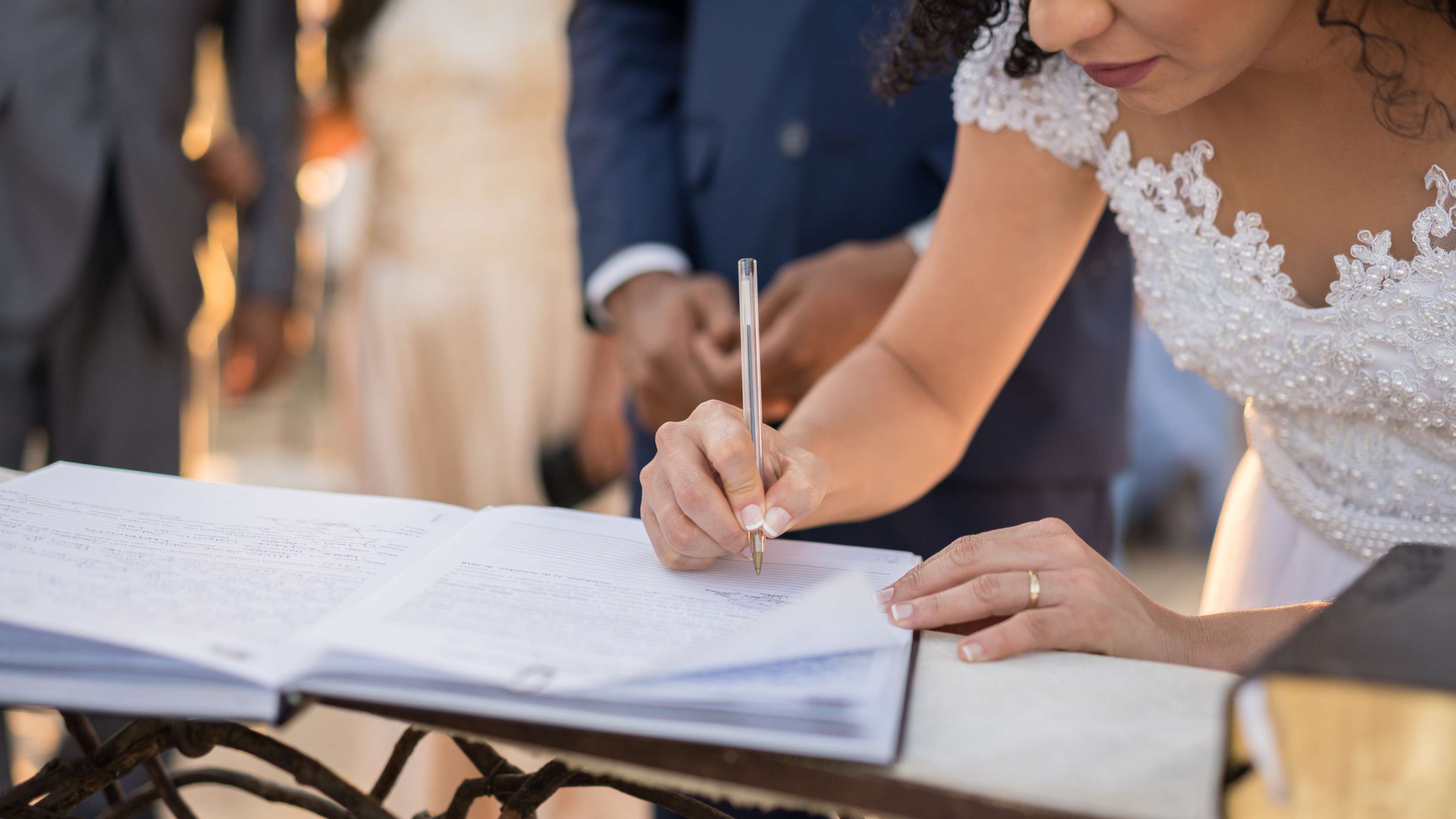 Auf dem Standesamt: Frau im Brautkleid unterschreibt ein Dokument