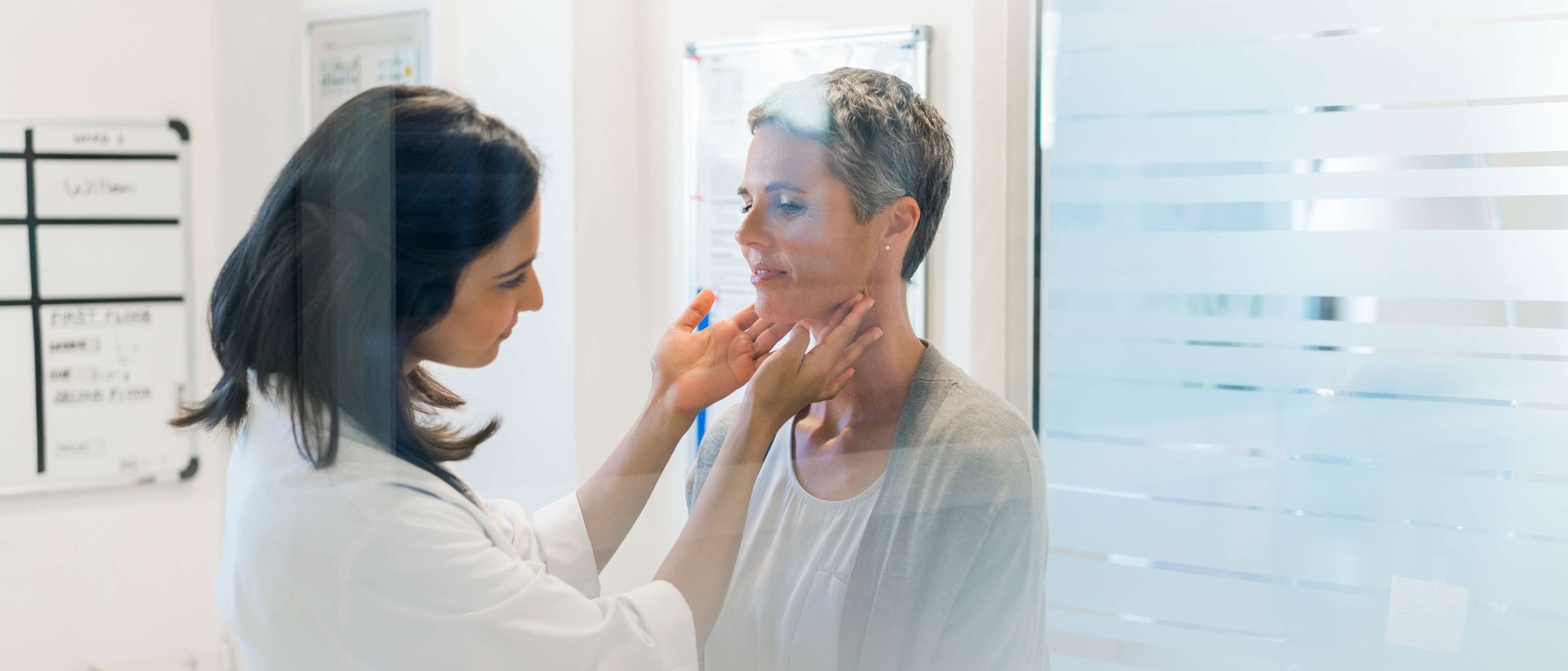 Arzttermin während der Arbeitszeit: Eine Ärztin überprüft den Hals einer Patientin