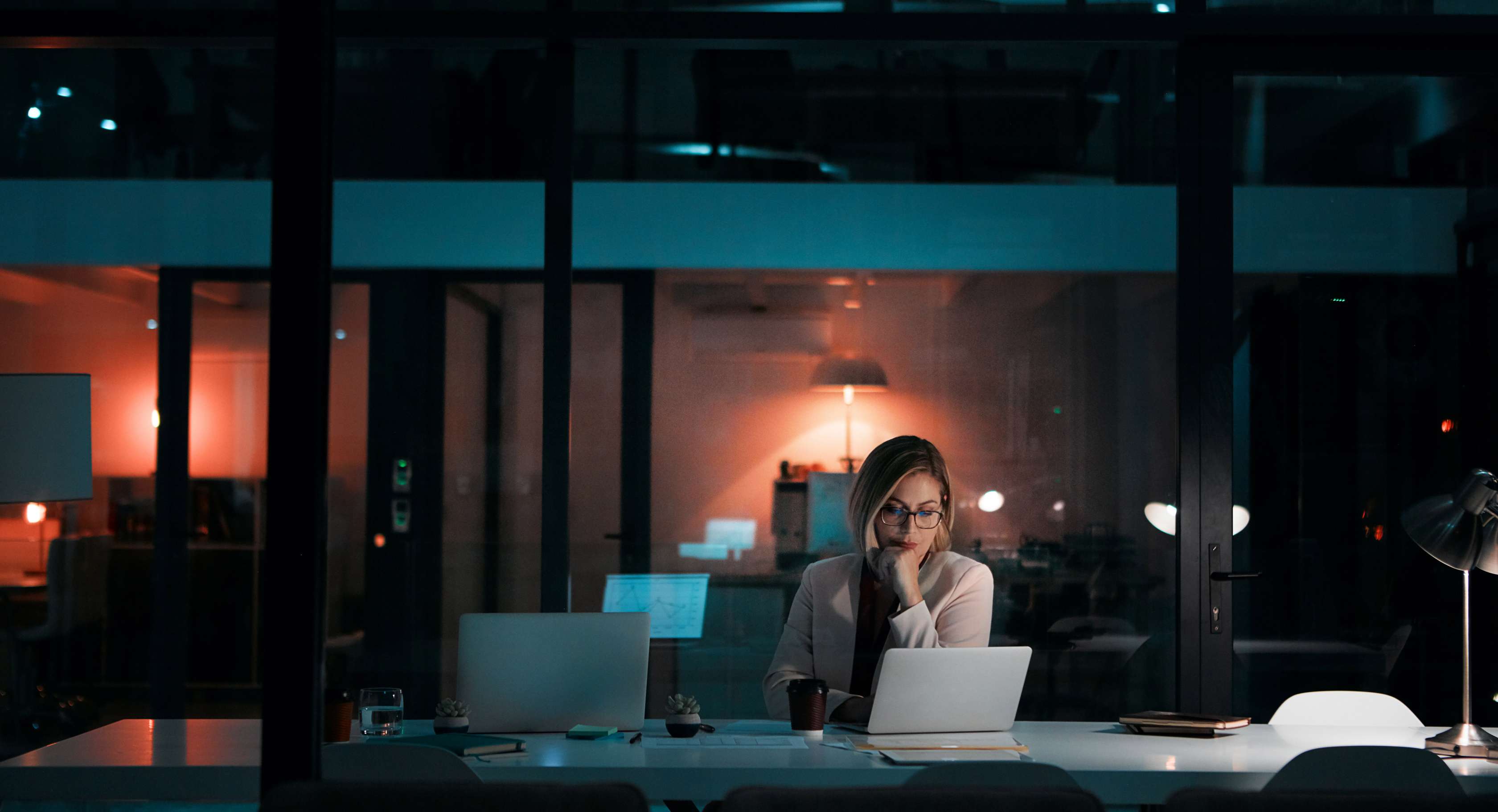 Überstunden: Eine Frau sitzt in einem dunklen Büro am Schreibtisch