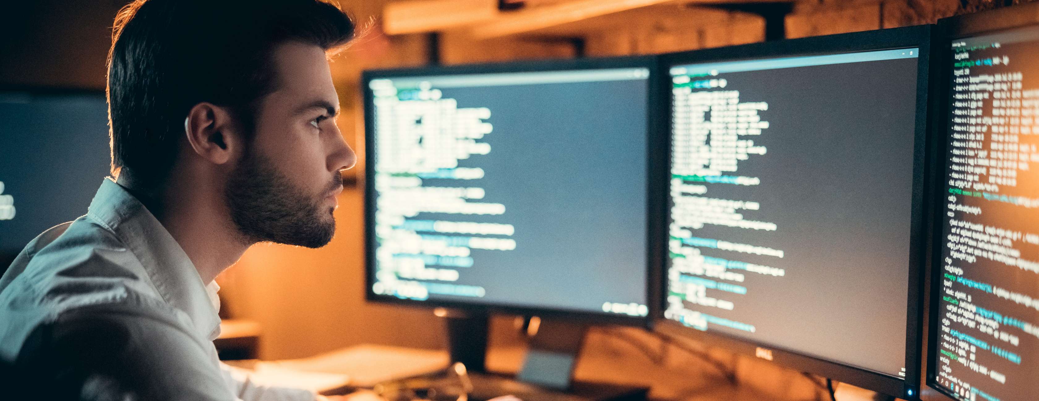 Mann schaut auf Bildschirme mit Code