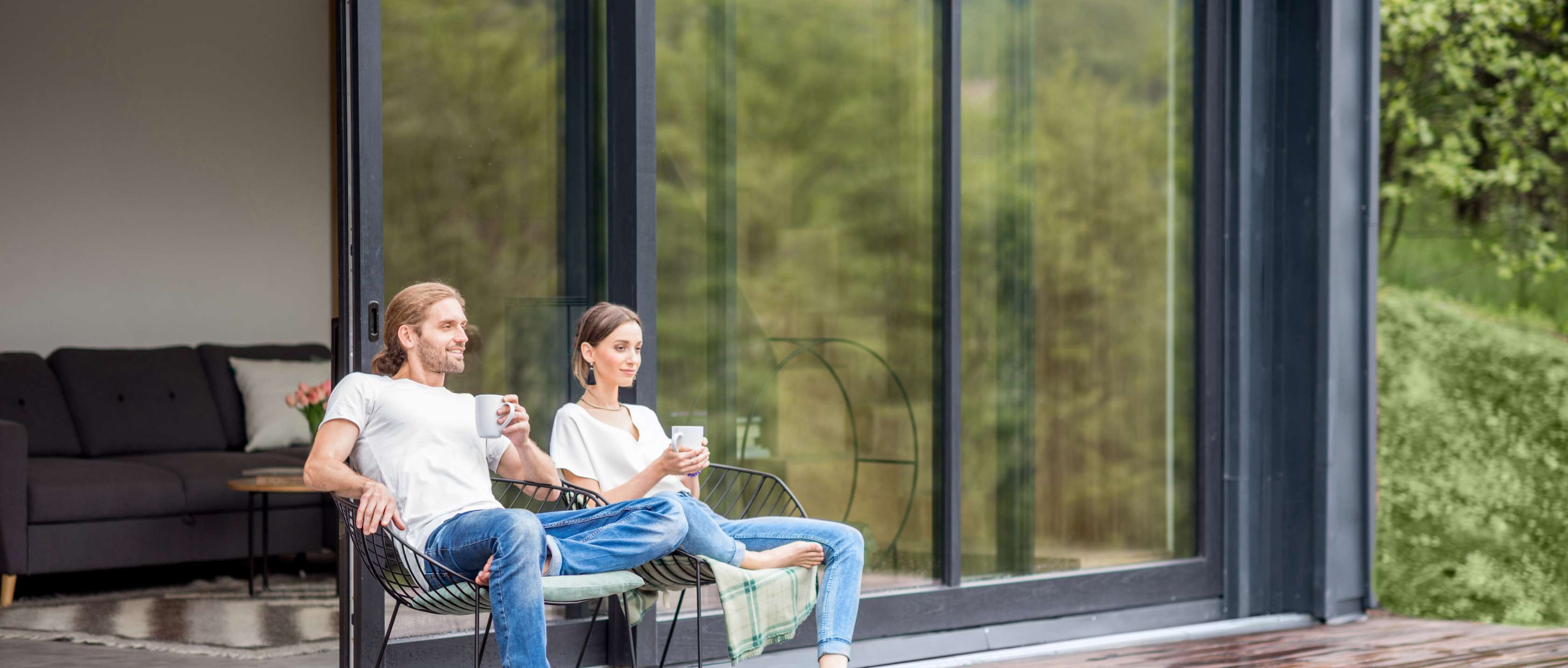Ein Paar sitzt entspannt auf der Terrasse vor seinem Haus 
