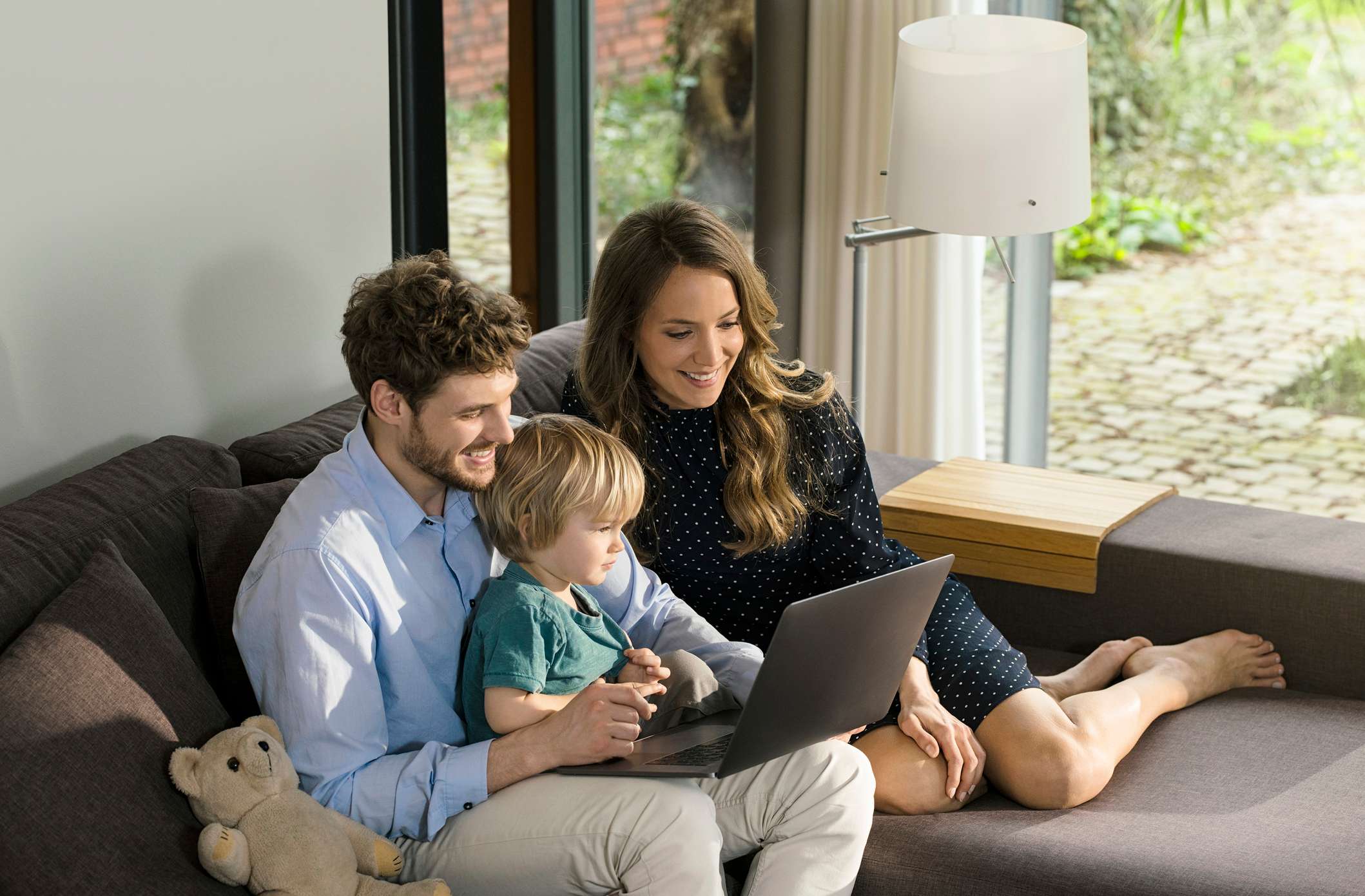 Wohngebäudeversicherung kündigen: Junge Familie sitzt zusammen auf dem Sofa und schaut sich Häuserangebote an