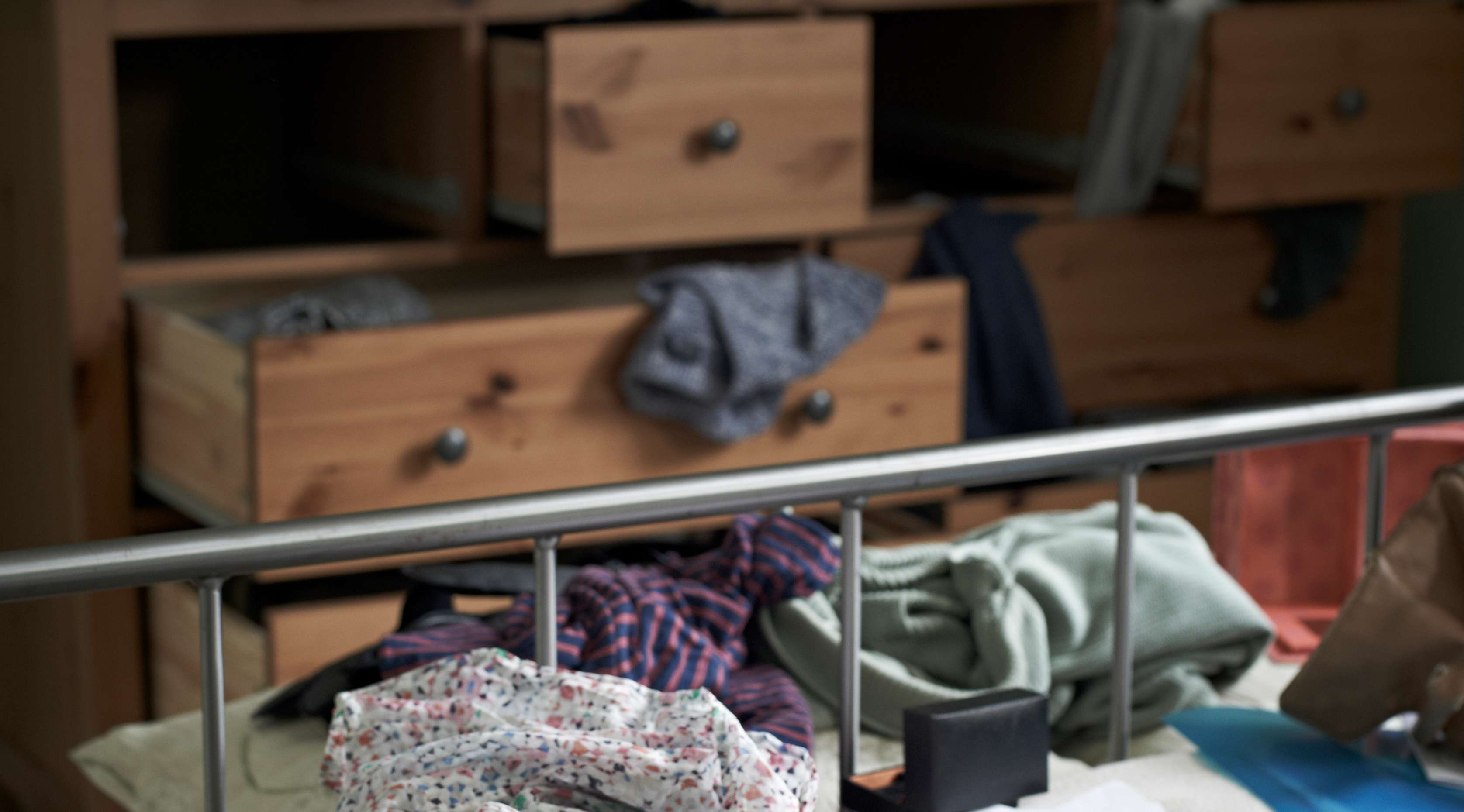 Offene Schubladen mit herausgerissener Kleidung in durchsuchter Wohnung