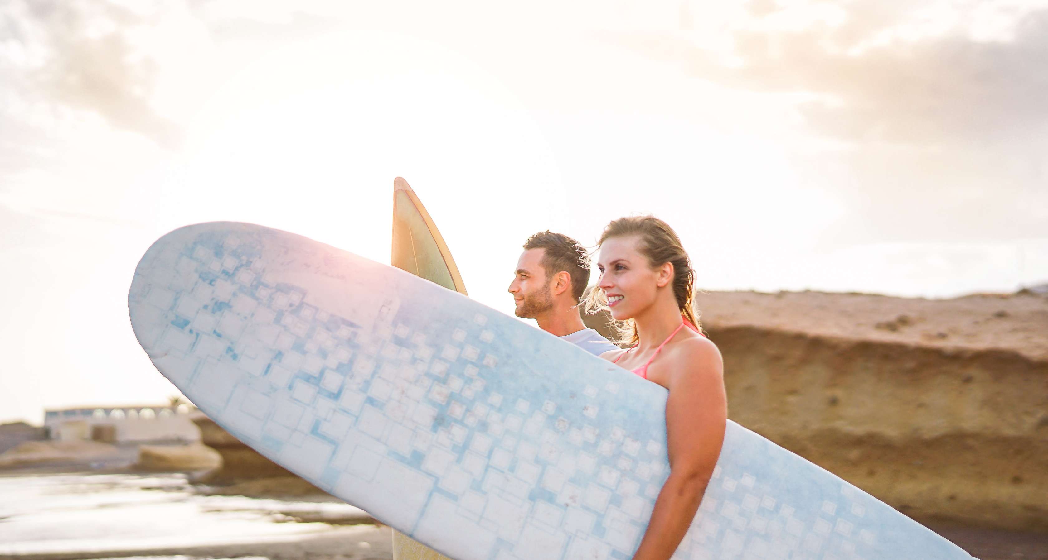 Junges Paar mit Surfbrettern am Strand