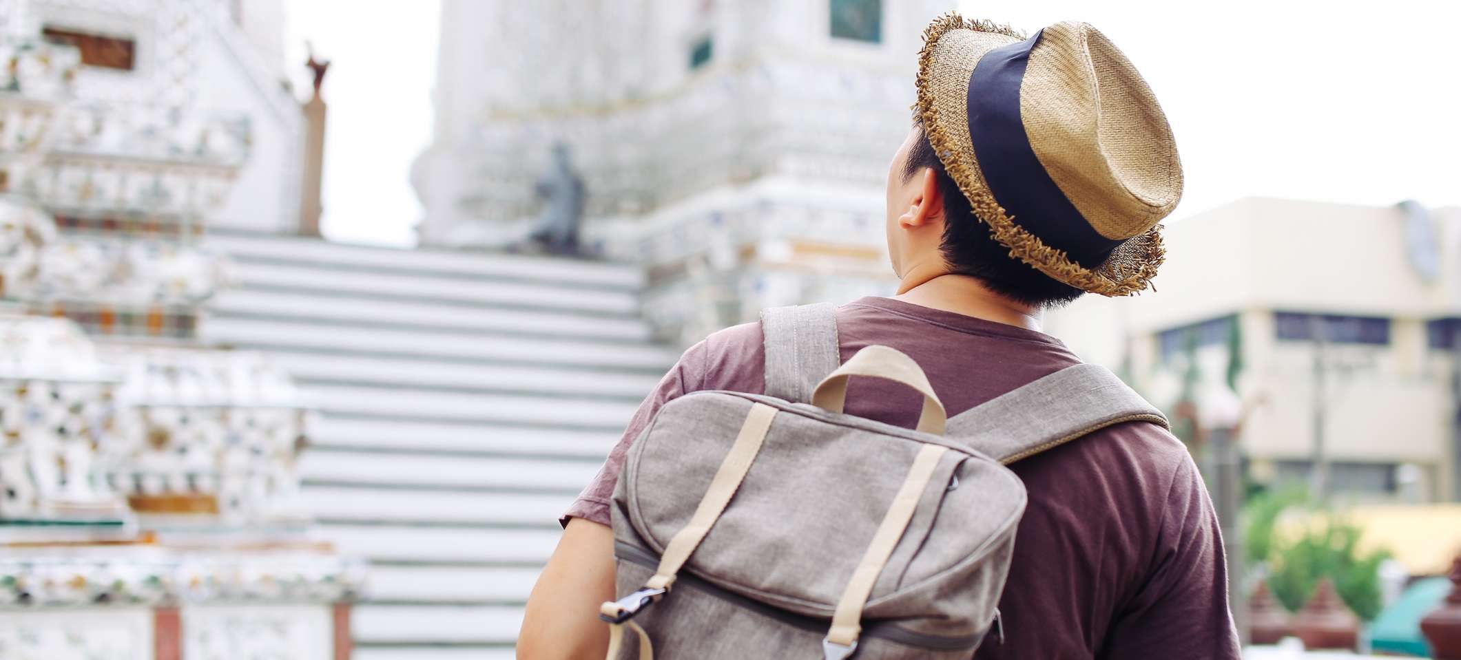 Tourist mit Rucksack und Strohhut schaut auf zu einem Tempel.