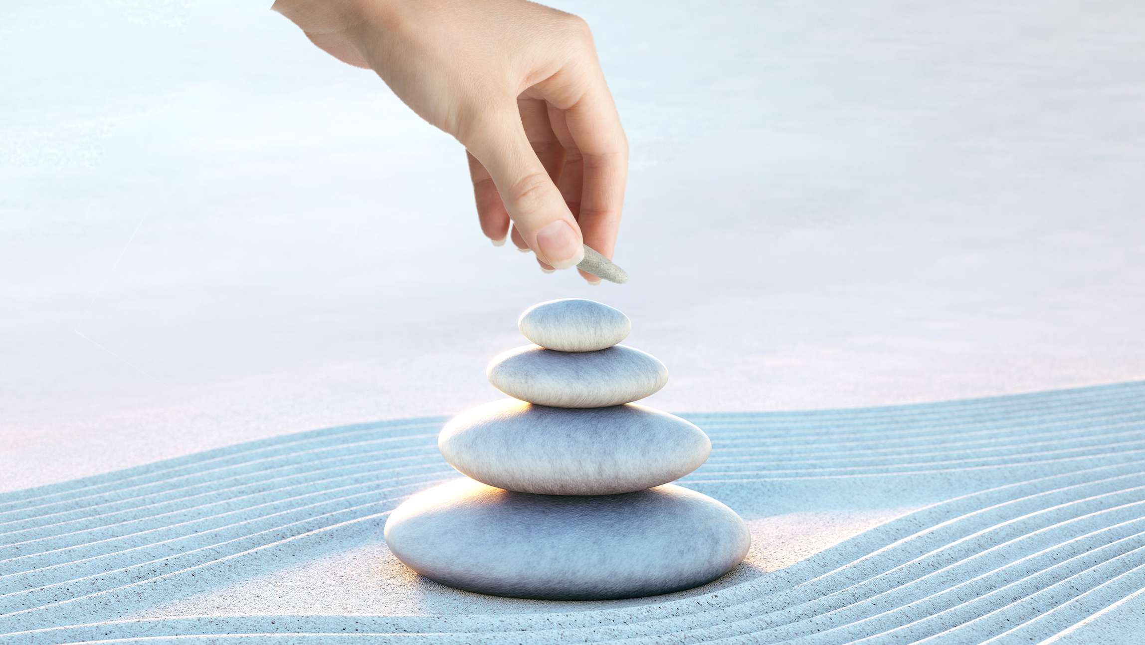 Allianz SchatzBrief: Steinstapel am Strand, Finger einer Frau legen einen Stein auf den Stapel