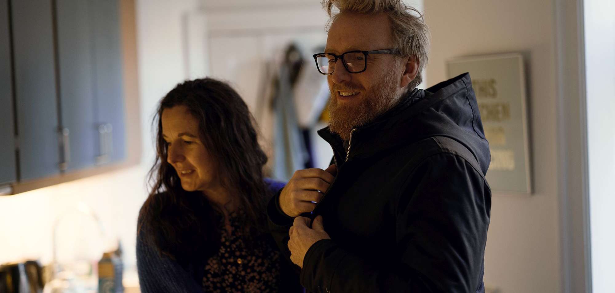 Allianz SchatzBrief: Paar steht in der Küche und begrüßt sich.