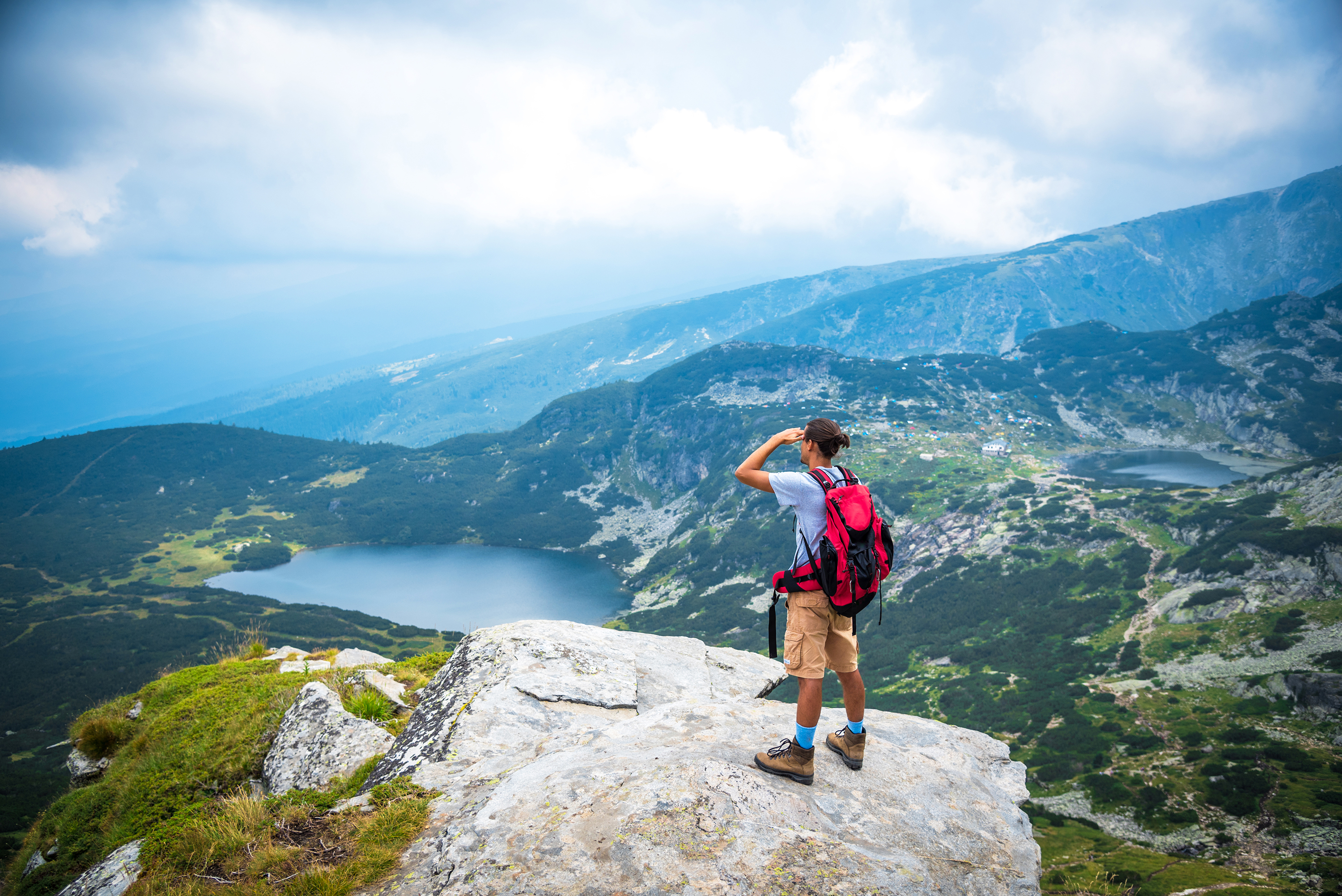 Wanderer steht auf einem Berg und schaut auf die Seven Rila Lakes hinab.