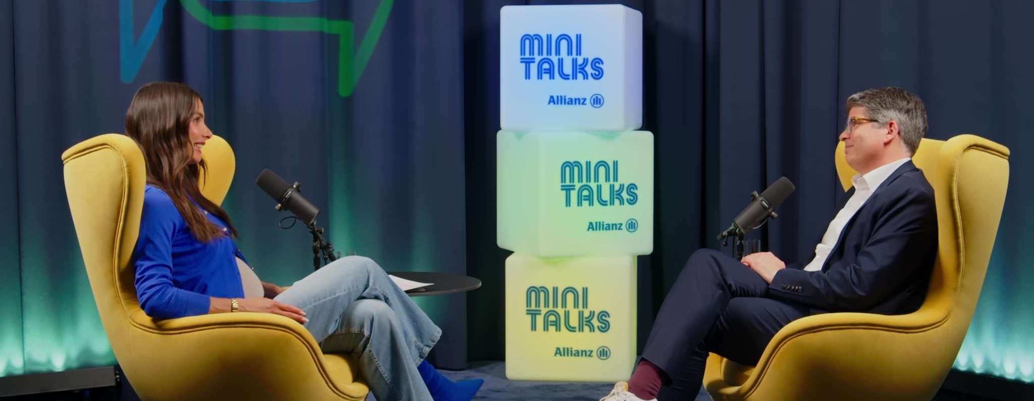Allianz MiniTalks Folge 13 Investieren vs. Sparen: Lea Wagner und Sebastian sitzen im Studio auf zwei Sesseln.