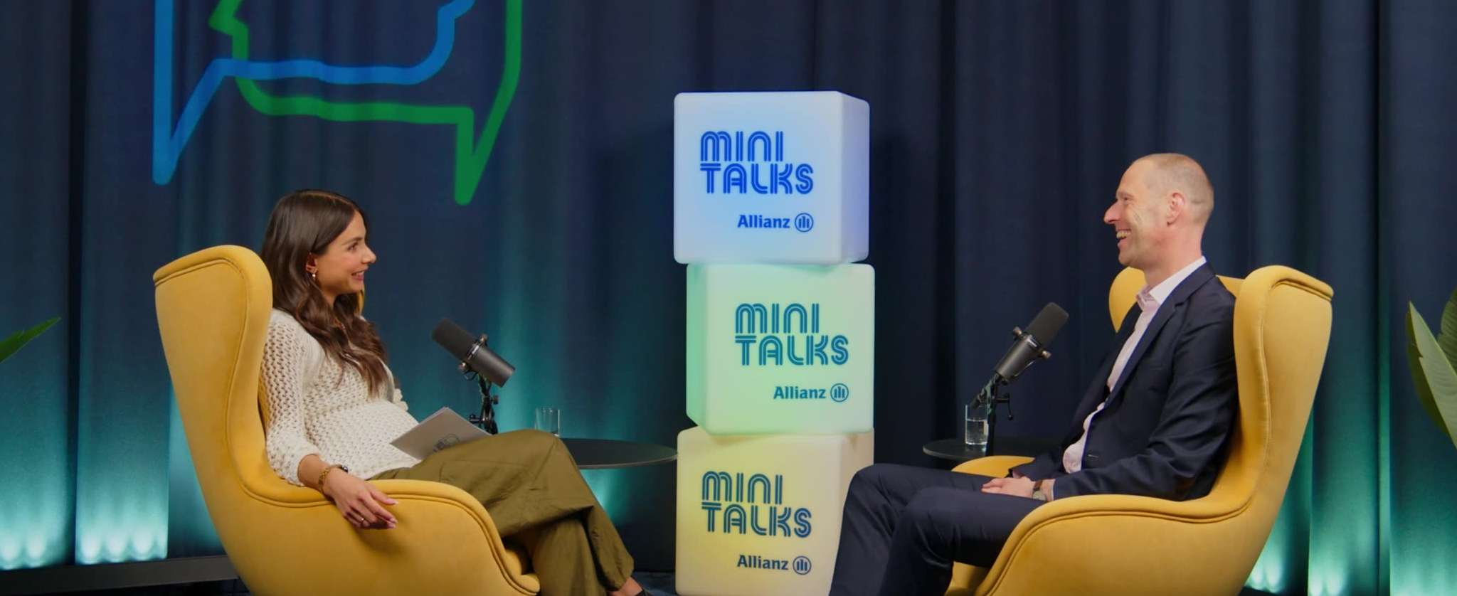 Allianz MiniTalks Folge 14 betriebliche Altersversorgung: Lea Wagner und Markus sitzen im Studio auf zwei Sesseln.