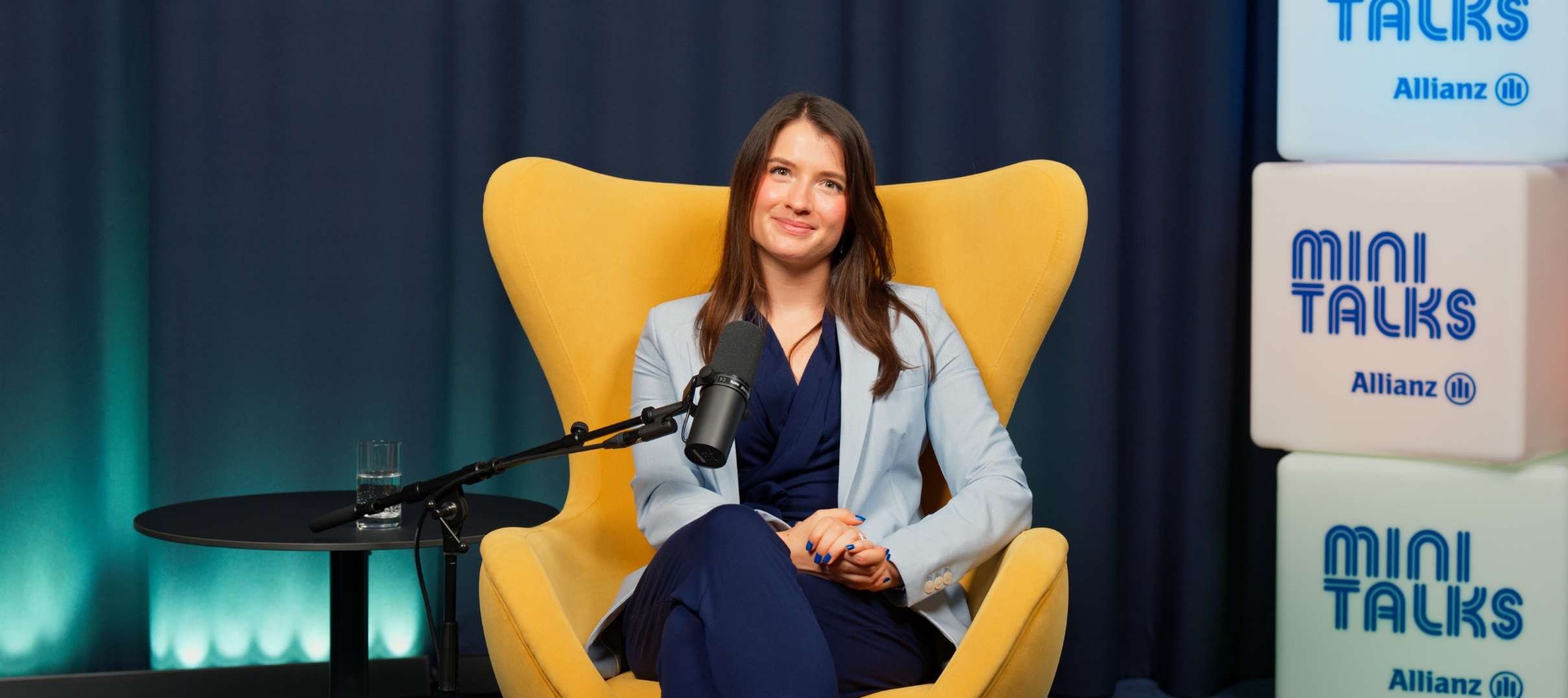 Allianz MiniTalks Folge 18 Altersvorsorgedepot einfach erklärt: Diese drei Varianten stehen zur Verfügung: Julia sitzt im Studio auf einem Sessel.
