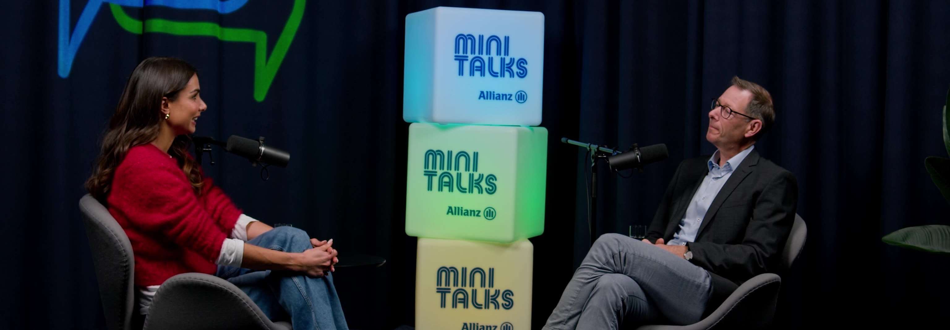 Allianz MiniTalks Folge 4 Geldanlage: Lea Wagner und Andreas sitzen im Studio auf zwei Sesseln.