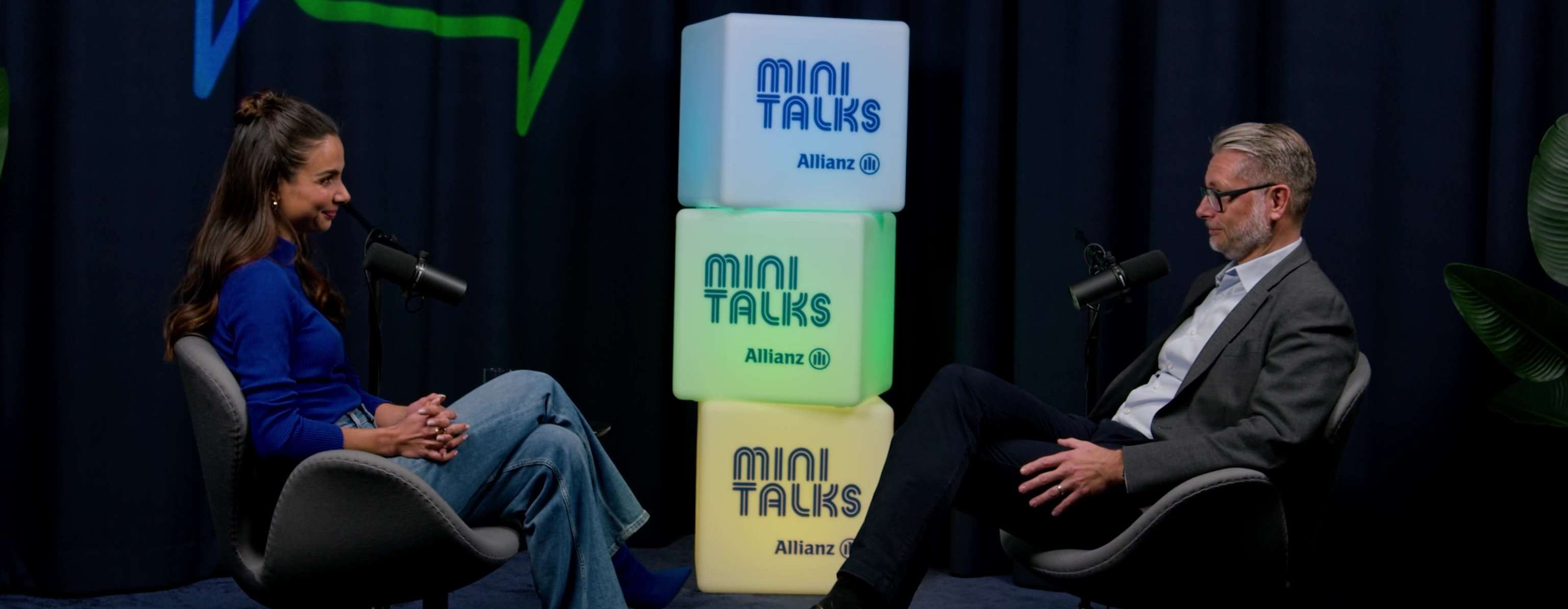 Allianz MiniTalks Folge 6 Drei Säulen der Altersvorsorge: Lea Wagner und Marcel sitzen im Studio auf zwei Sesseln.
