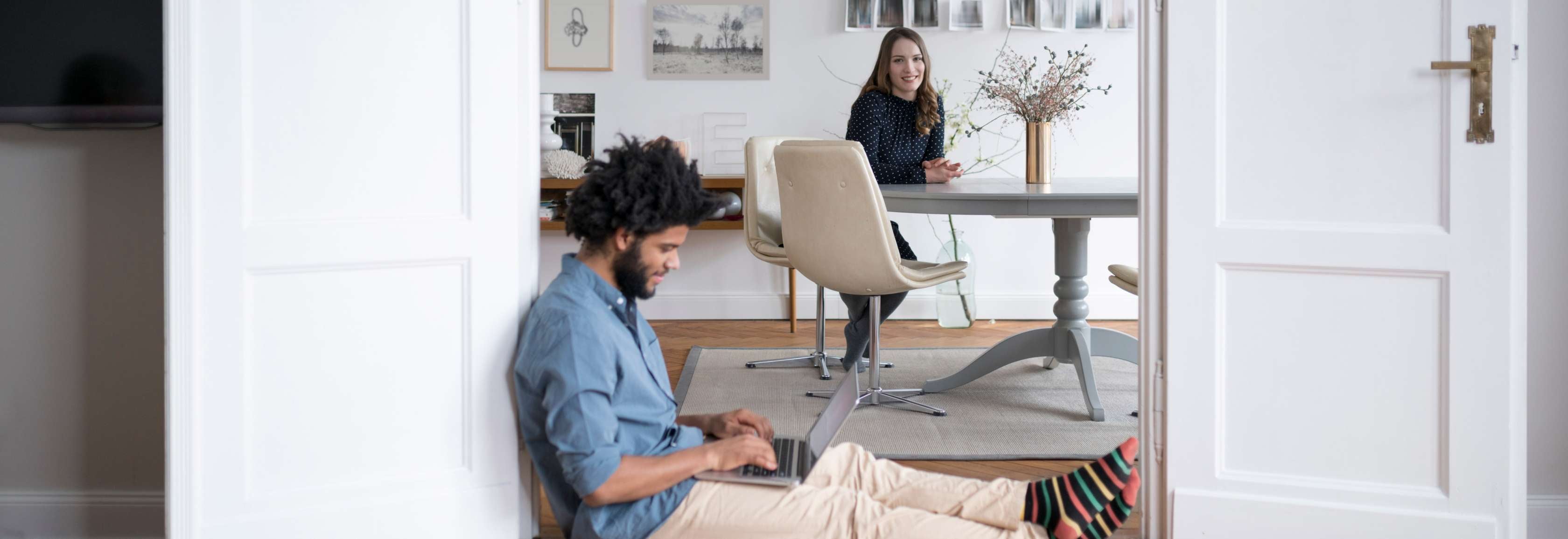 Versicherungskosten-berechne: Junges Paar zuhause im Wohnzimmer mit Laptop