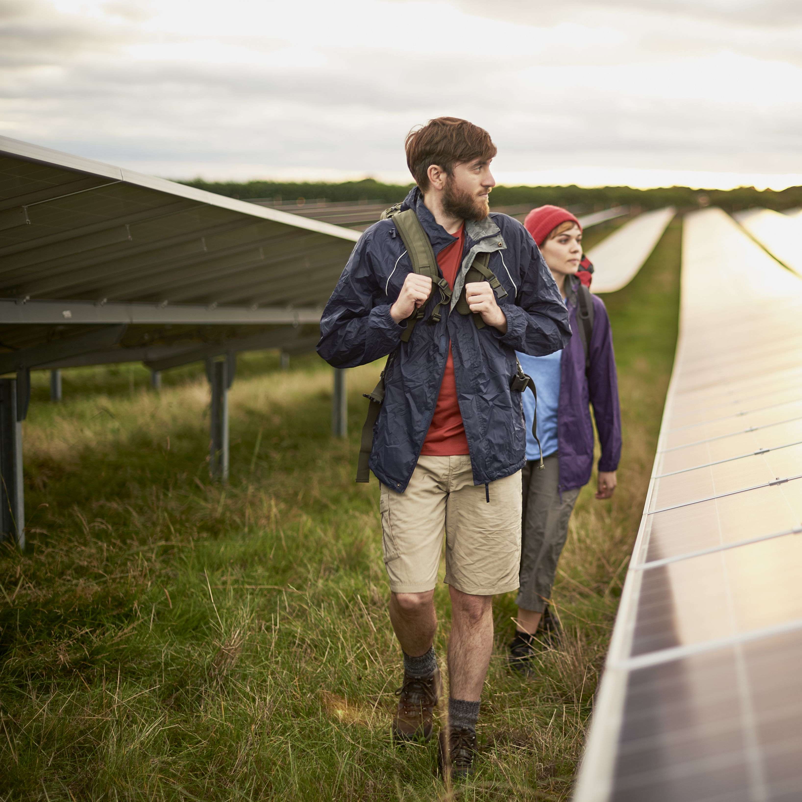 Zwei junge Menschen spazieren auf einer Wiese zwischen Solarpanels