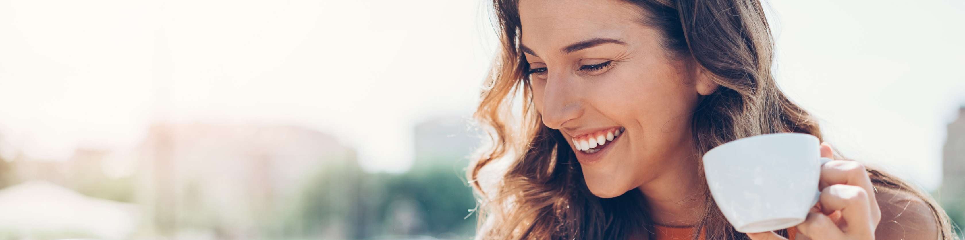 Allianz Vorsorge: Eine junge Frau sitzt vor einem Laptop und hält eine Tasse in der Hand