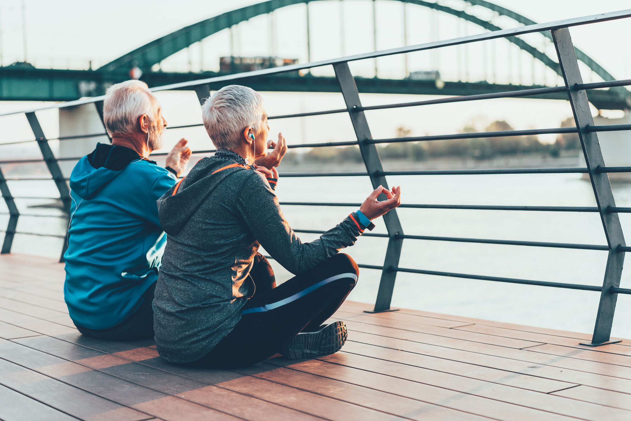 Allianz - Altersvorsorge - Alternativen: Älteres Paar sitzt beim Meditieren am Flußufer