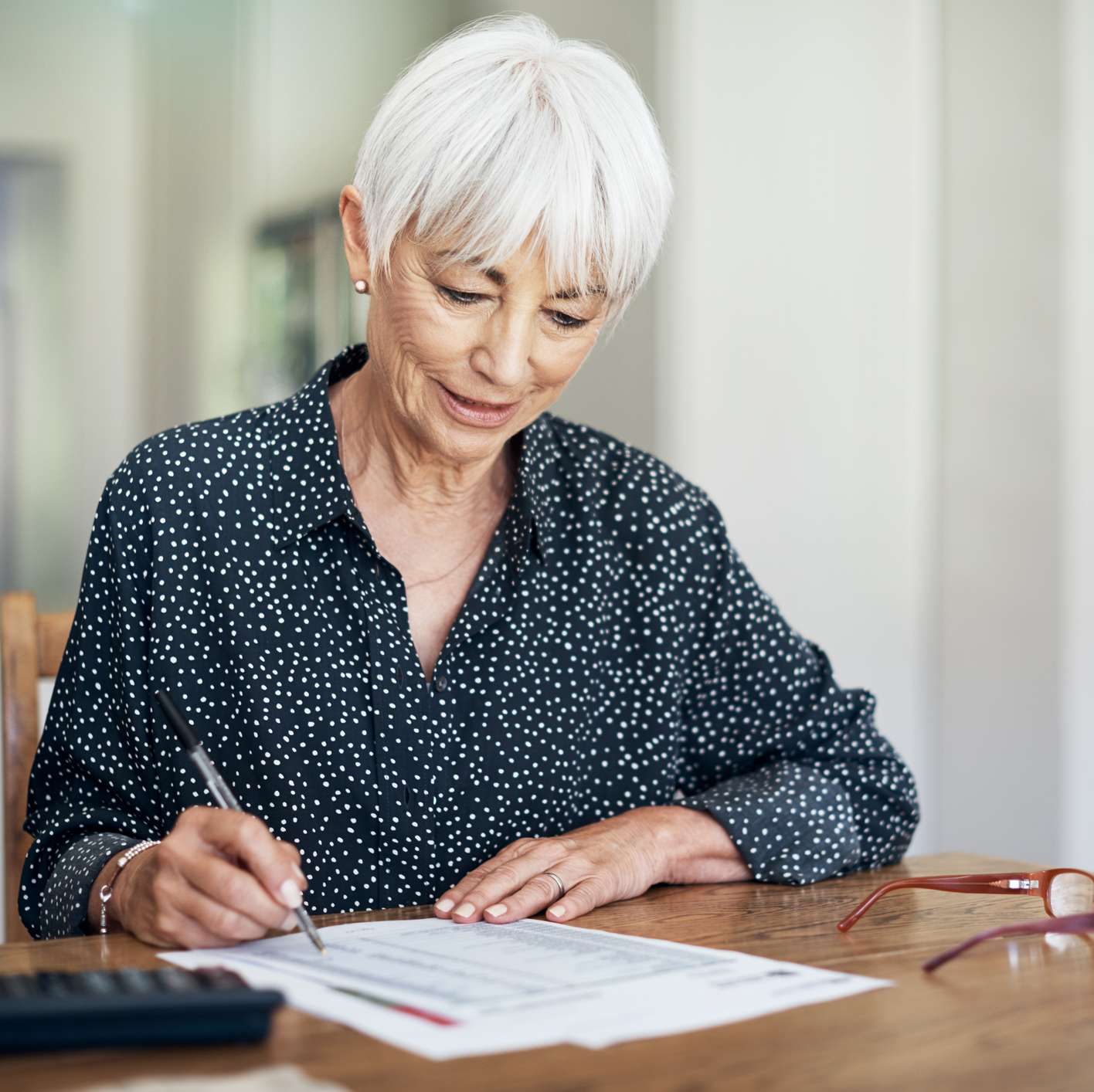 Allianz - Altersvorsorge - Rentenversicherungen: Eine weißhaarige, ältere Frau, schreibt etwas in eine Liste