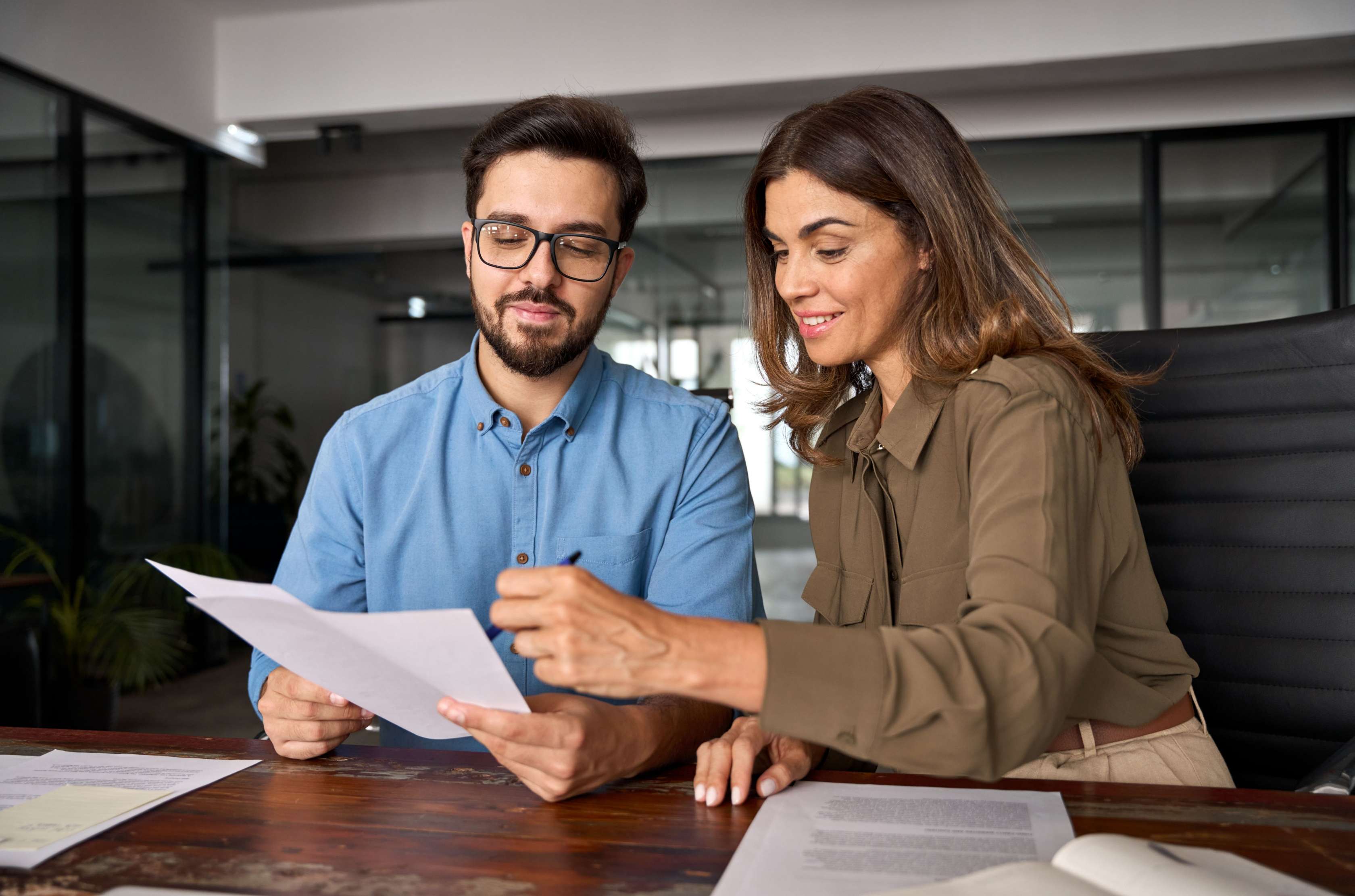 Eine Frau und ein Mann sitzen an einem Tisch und schauen gemeinsam auf ein Dokument.