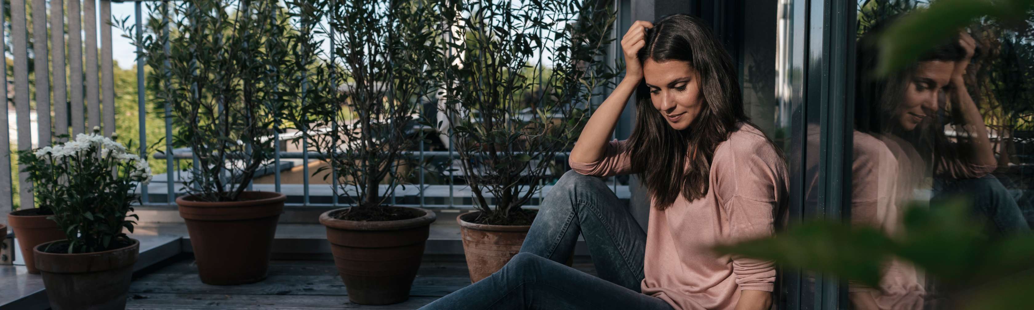 Allianz Berufsunfähigkeitsversicherung: sinnvoll oder nicht - Eine Frau sitzt am Boden, greift sich nachdenklich an den Kopf und schaut dabei in einen Laptop. 