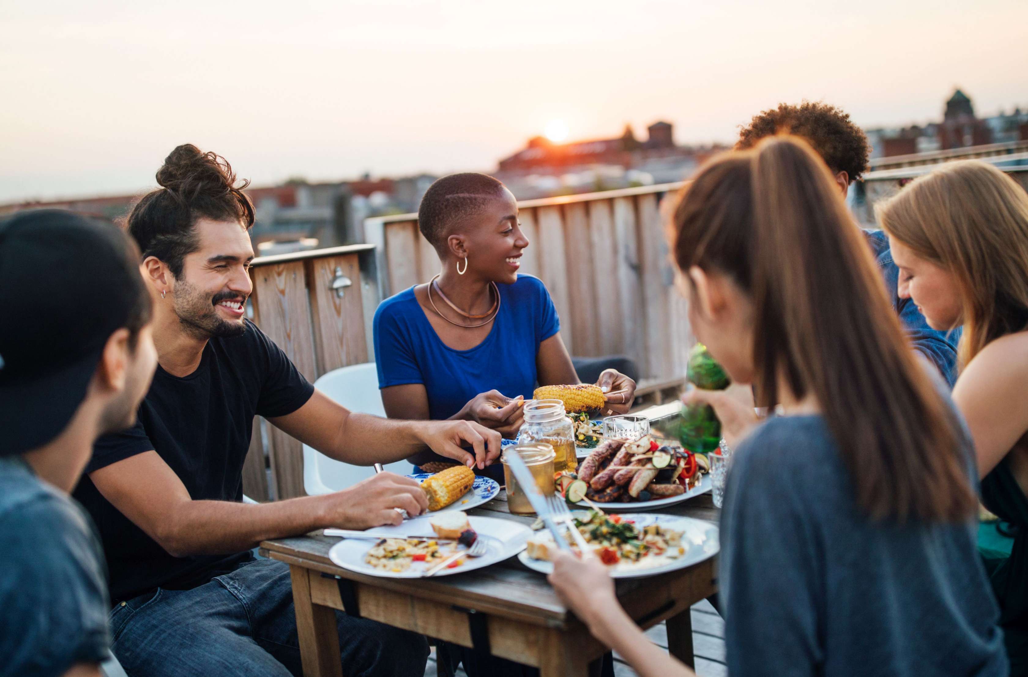 Allianz Berufsunfähigkeit StartPolice: Viele junge Menschen sitzen um einen Tisch und essen