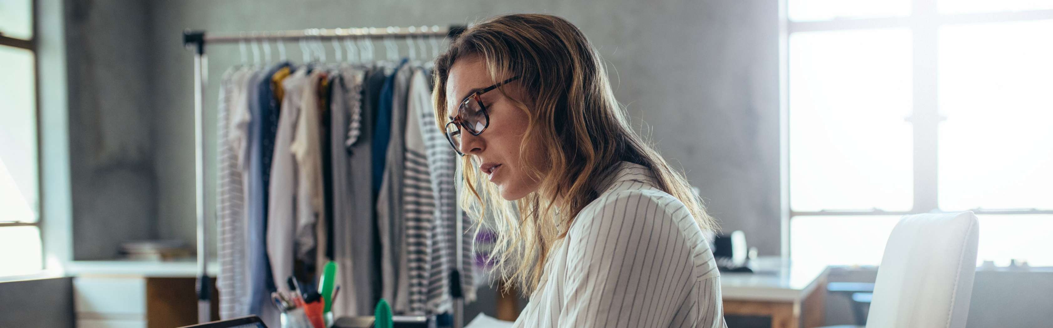 Allianz Zwei Berufsunfähigkeitsversicherungen - Eine Frau sitz in einem Zimmer am Schreibtisch und schaut auf einen Block.