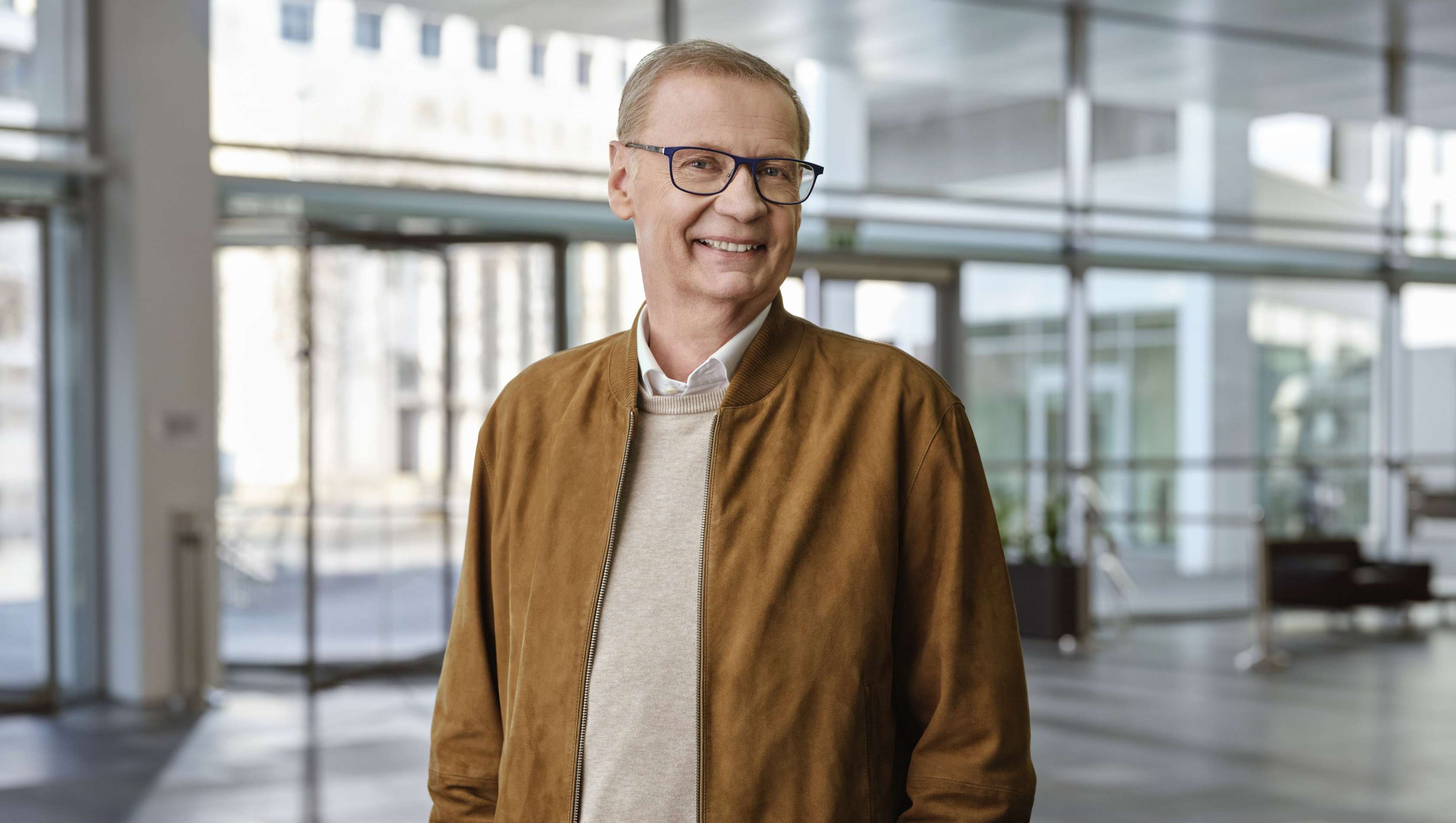 Günther Jauch schaut in die Kamera und steht in der Mitte eines Concept Stores.