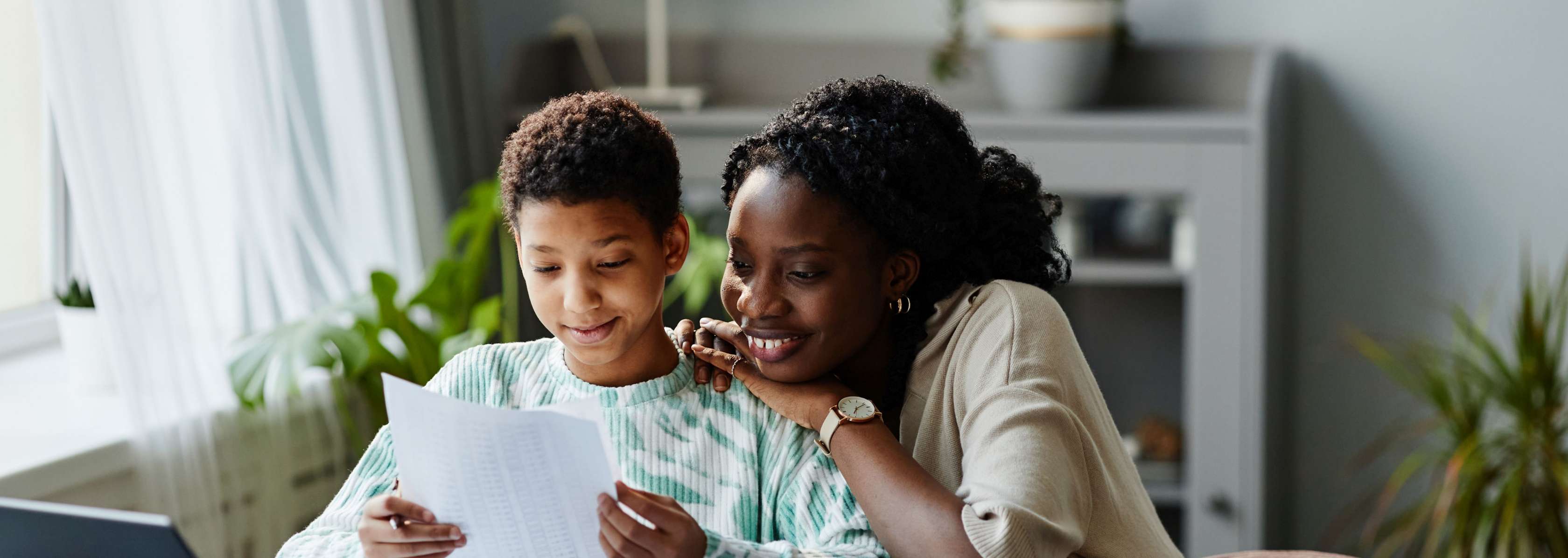 Allianz KinderPolice - Vormundschaft: Eine Frau und ein Kind schauen sich lächelnd Dokumente an.