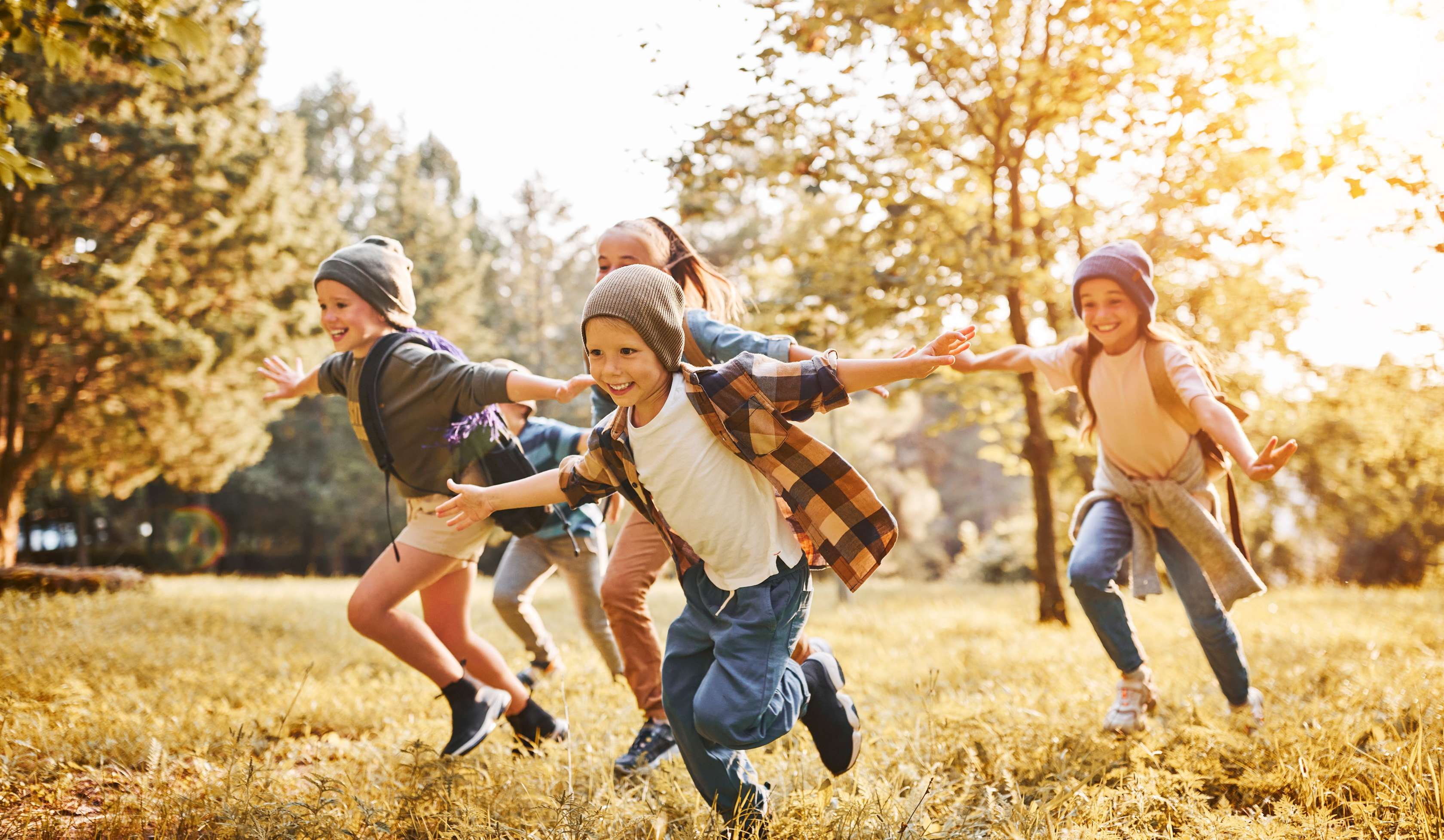 Vier Kinder laufen auf einer Wiese.