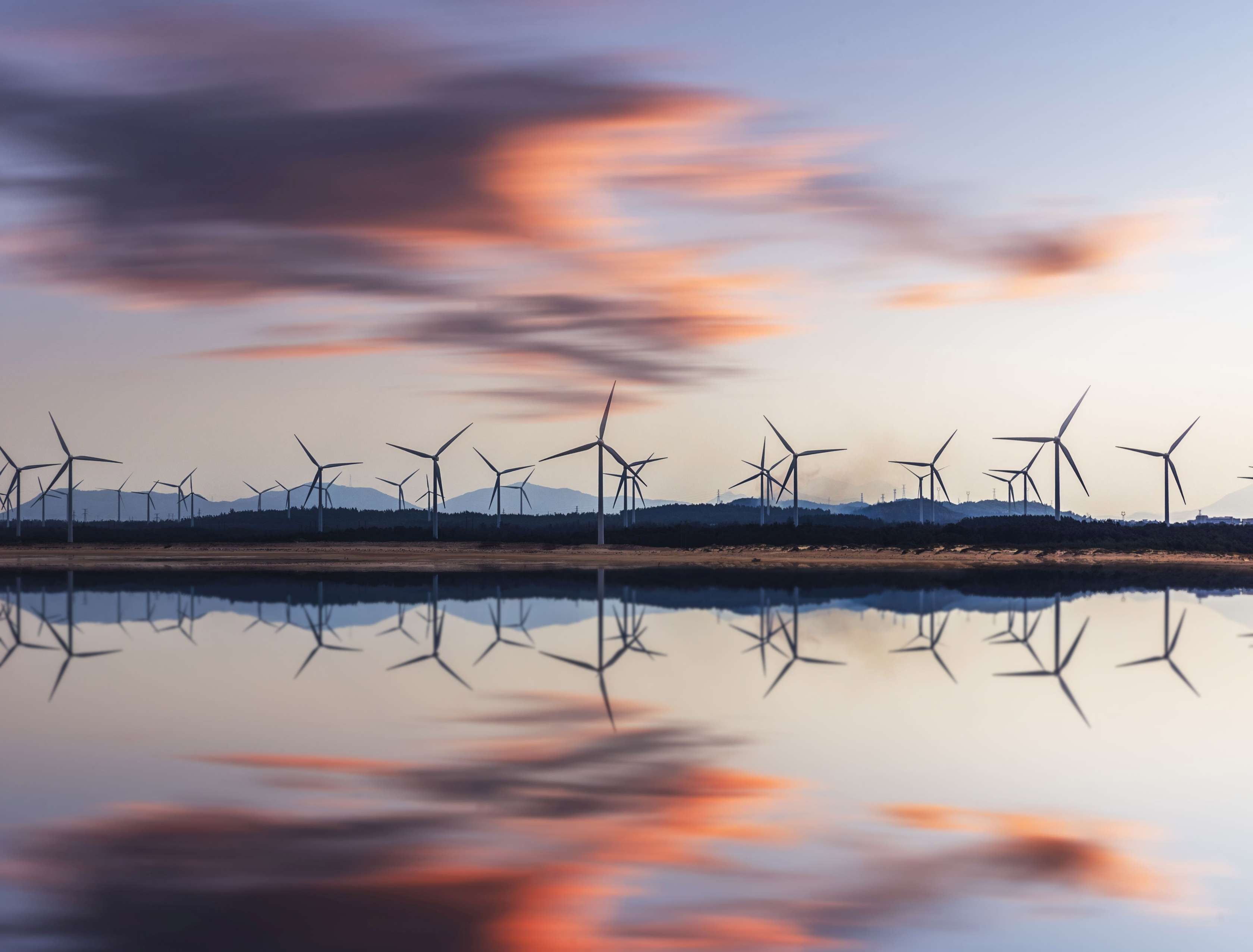 Windkrafträder spiegeln sich in einem See