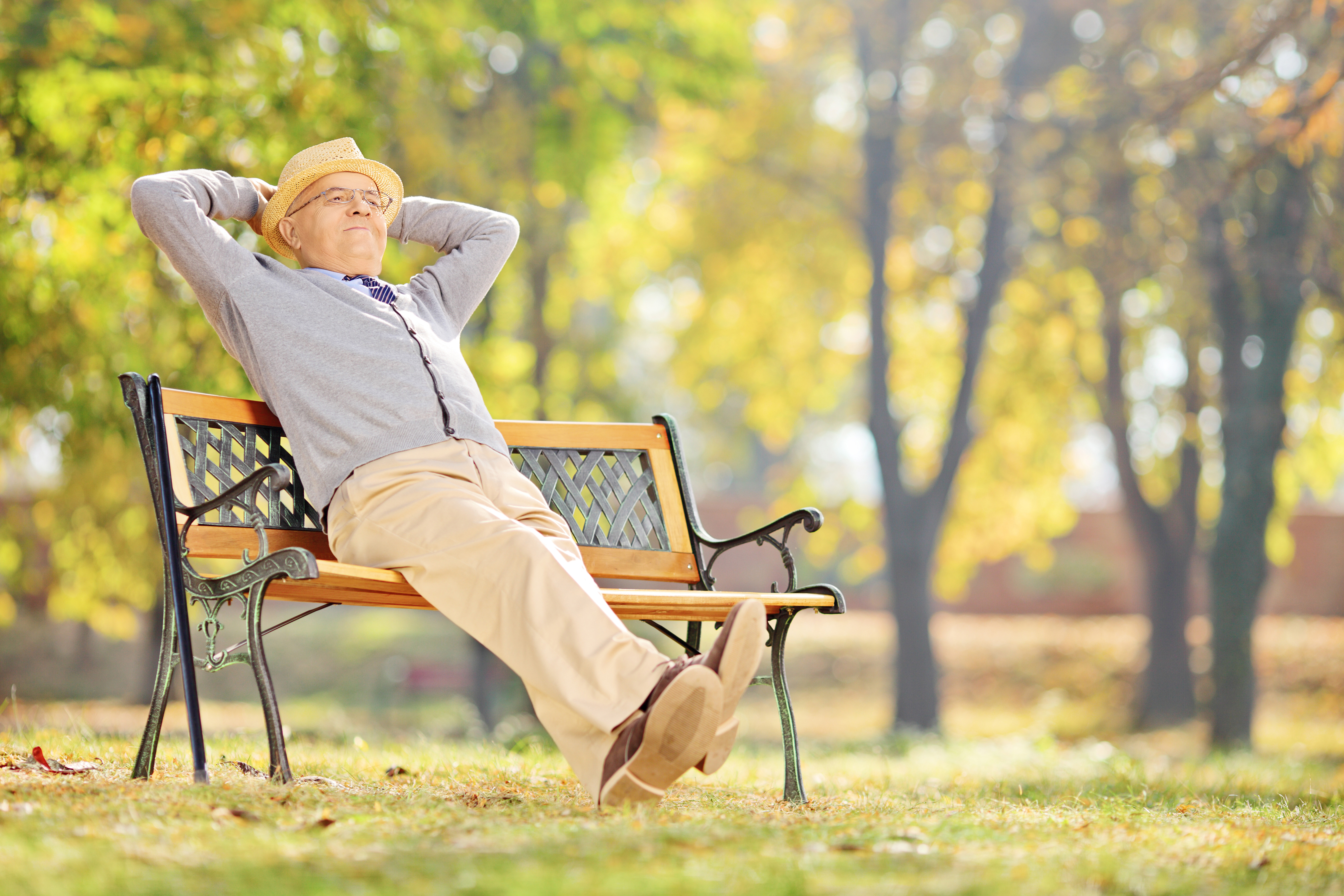 Allianz - Älterer Mann sitzt entspannt auf Parkbank