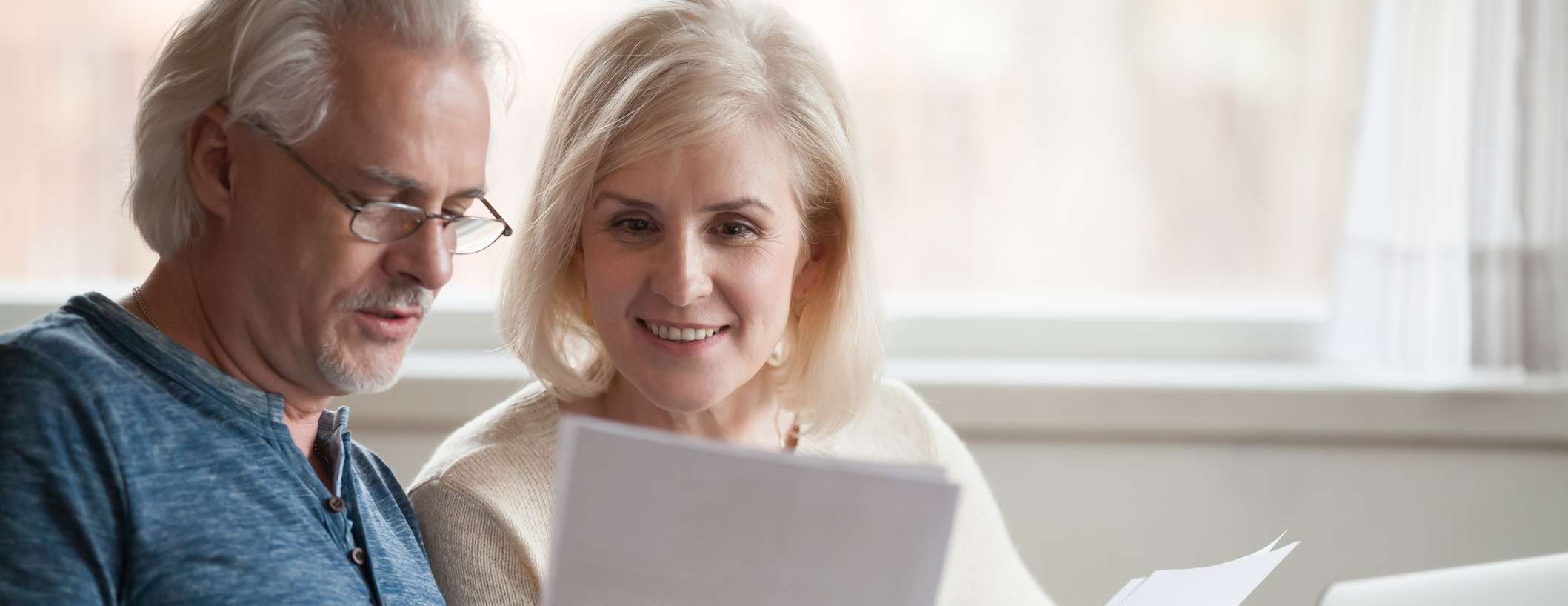 Allianz - Vorsorge - Rente aufstocken: Paar schaut sich Dokumente an. Die Frau lächelt.