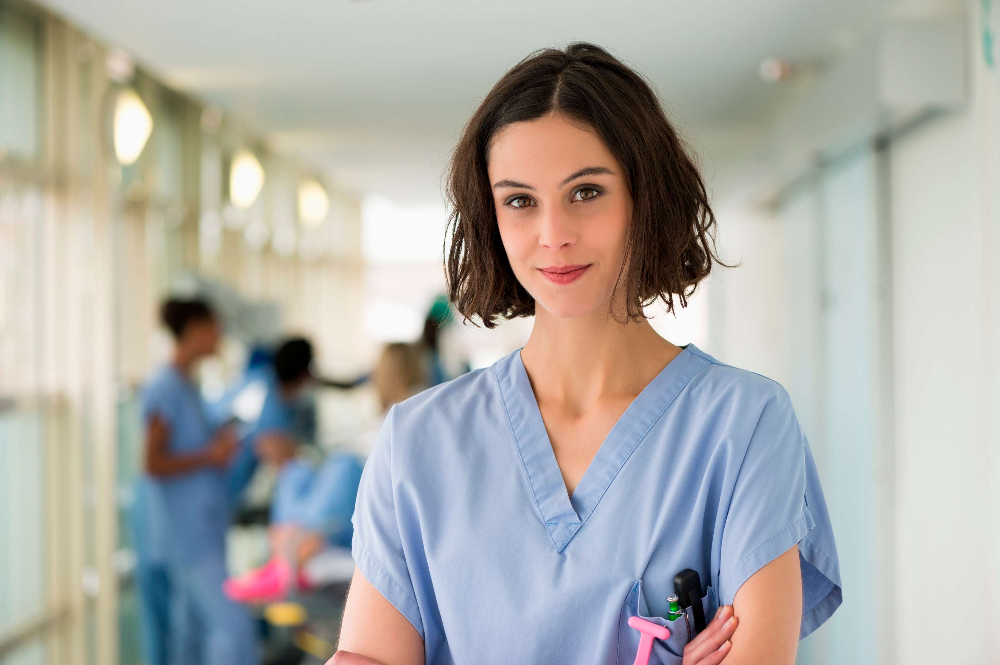 Allianz - Private und betriebliche Altersrente: Junge Krankenschwester mit Kolleginnen im Hintergrund