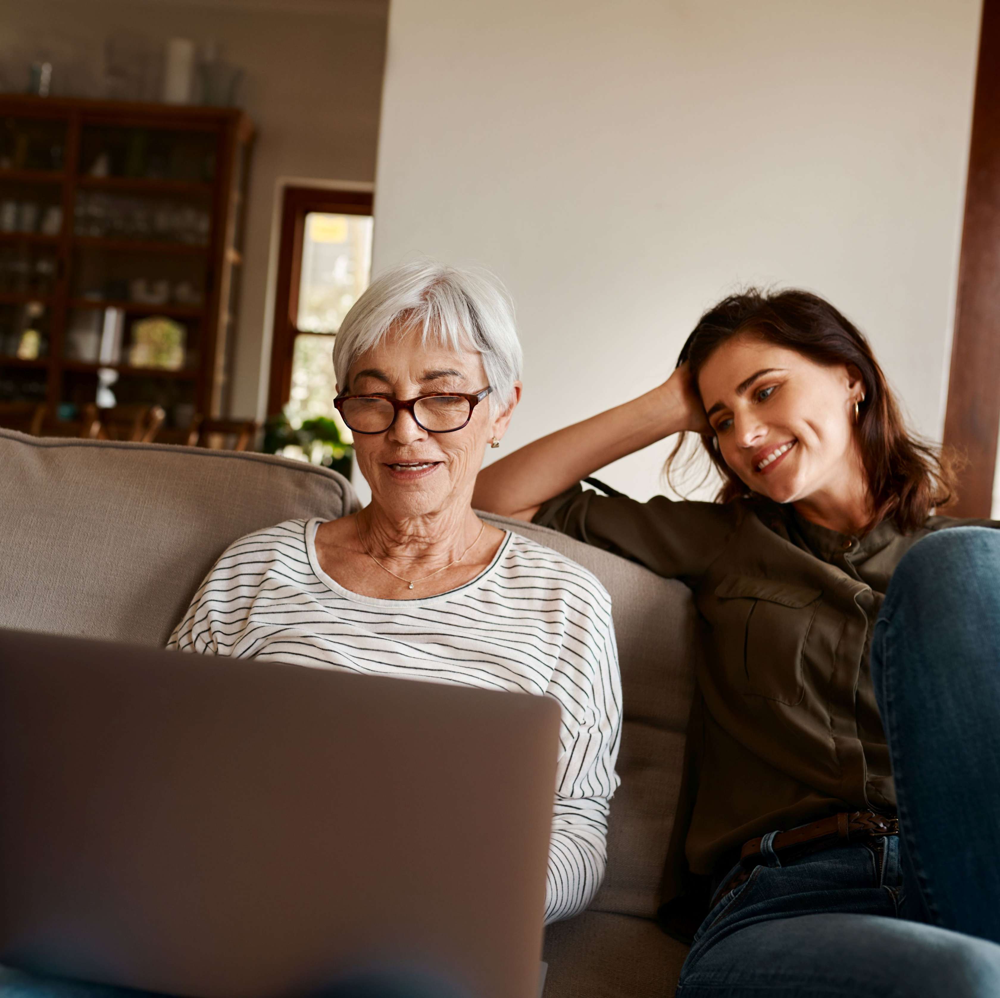 Risikolebensversicherun für Senioren und Rentner - Seniorin und junge Frau sitzen auf einem Sofa und schauen in einen Laptop
