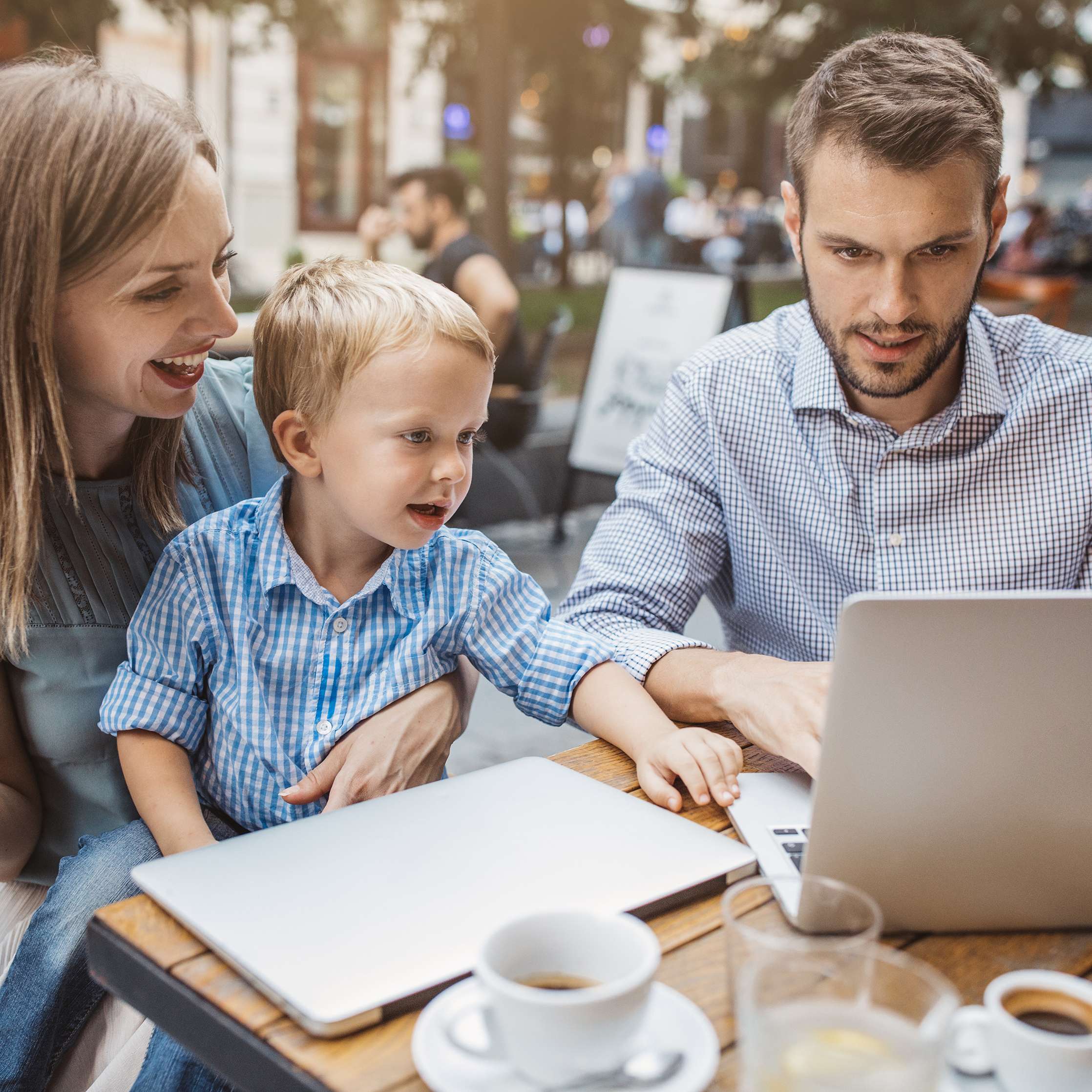 Junge Familie mit Kleinkind recherchiert Online in einem Cafe
