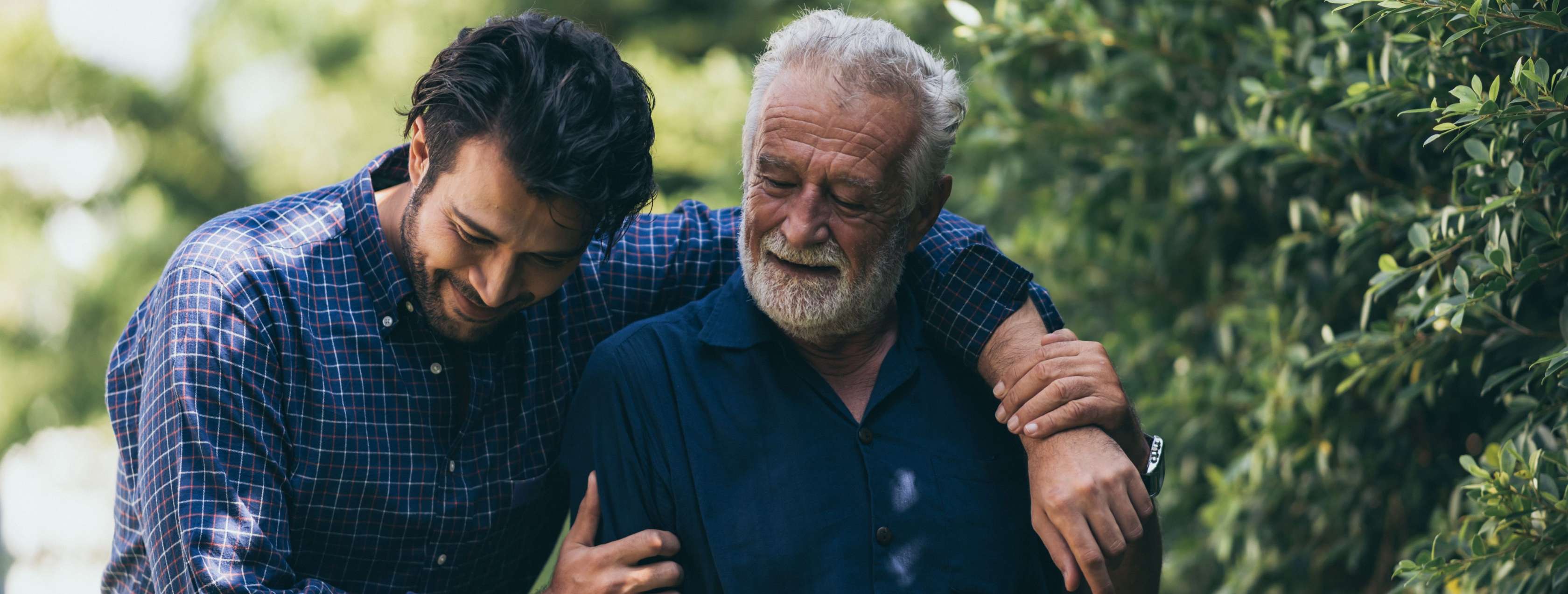 Allianz Sterbegeldversicherung ohne Wartezeit: Ein Mann geht Arm in Arm mit einem älteren Herren spazieren