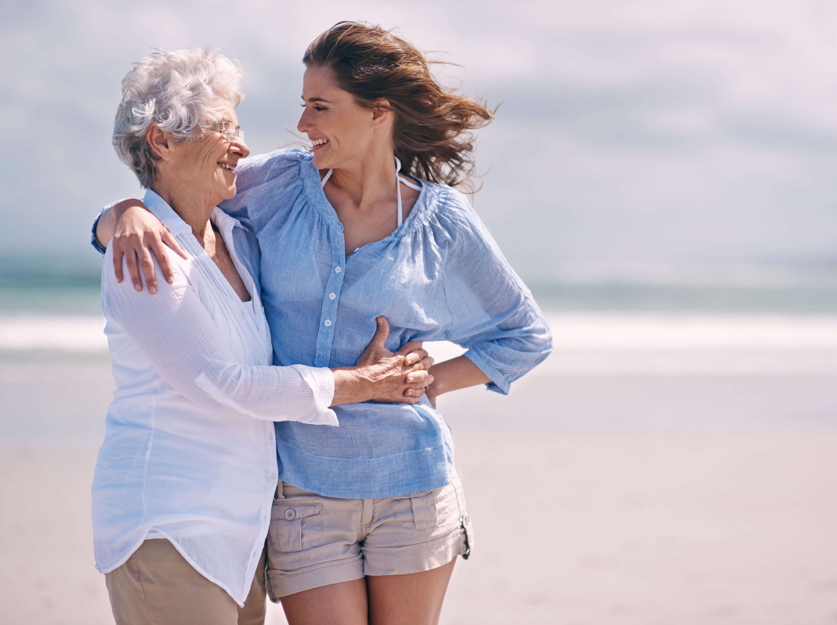 Allianz Bestattungsarten im Todesfall - Tochter umarmt Mutter am Strand.
