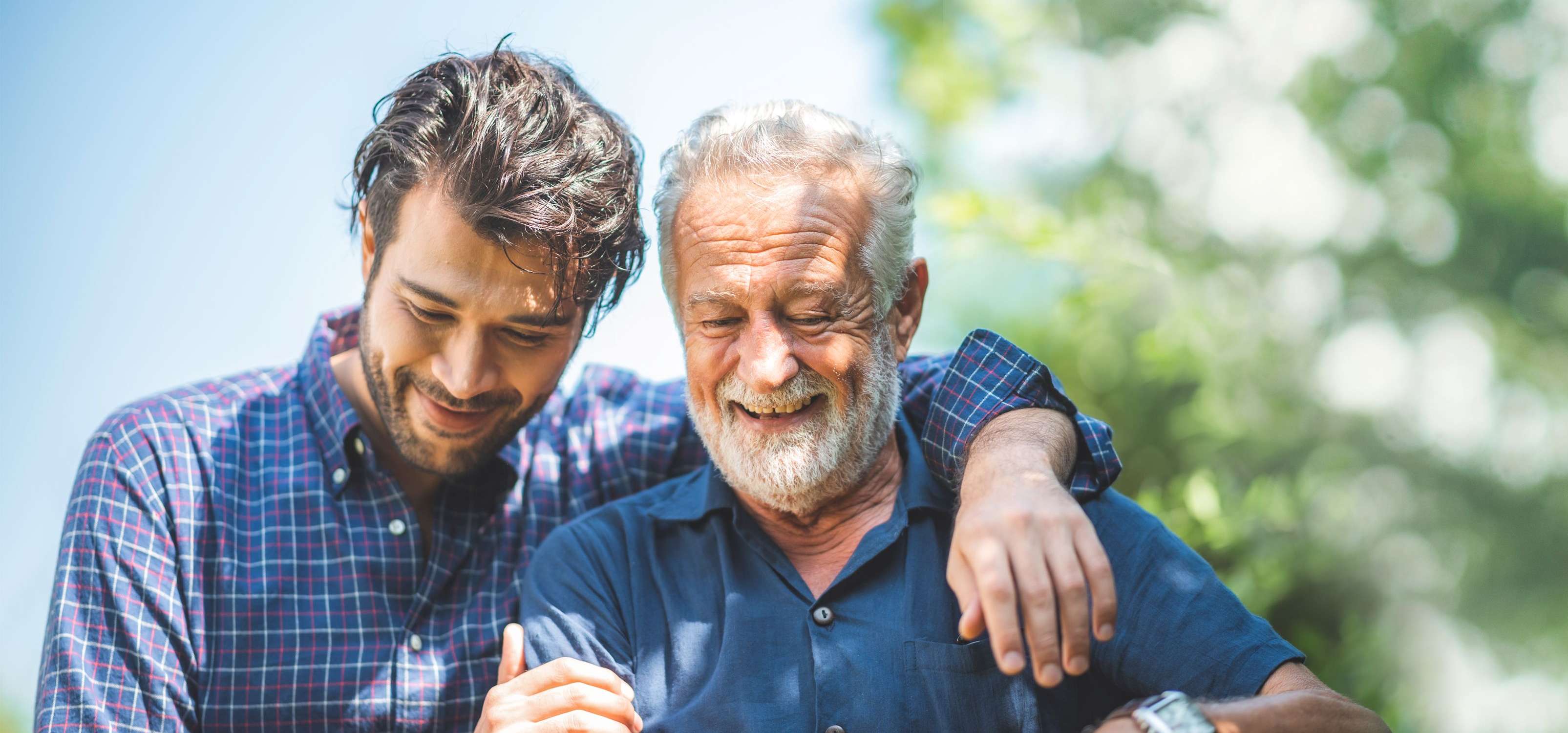Allianz Bestattungsvorsorge - Ein Sohn umarmt seinen Vater bei einem Spaziergang in der Natur.