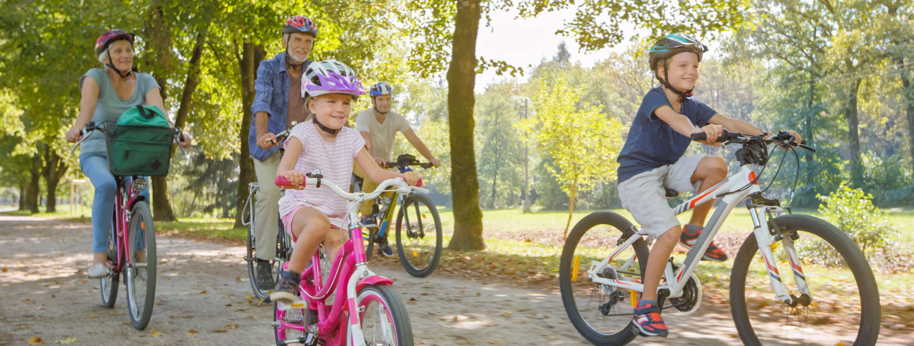 Allianz Unfallversicherung - Fahrradunfall: Oma und Opa fahren mit Enkel und Enkelin auf dem Fahrrad durch einen Wald