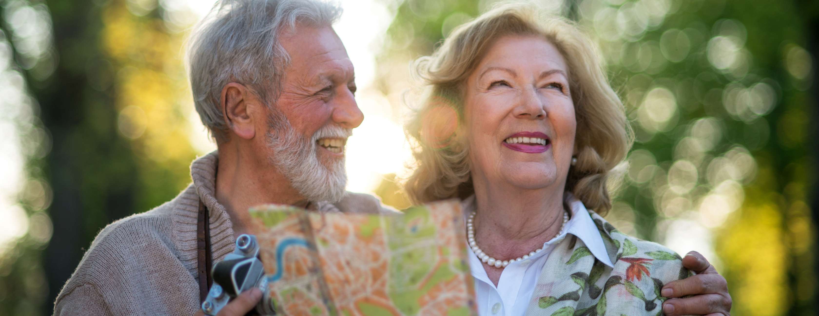 Allianz Kapital-UnfallSchutz: Älteres Ehepaar geht lächelnd im Grünen spazieren