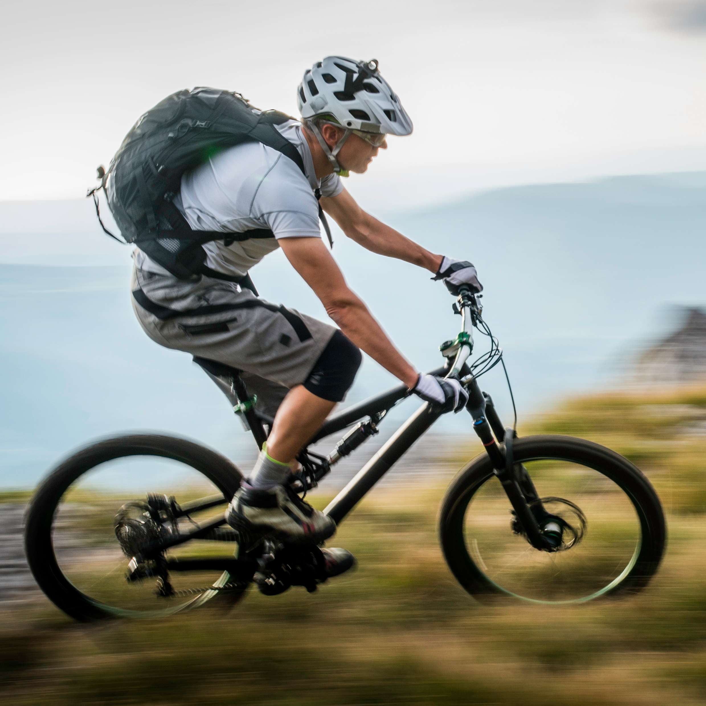 Allianz Kapital-UnfallSchutz für Erwachsene: Mountainbiker rast querfeldein durch Berglandschaft