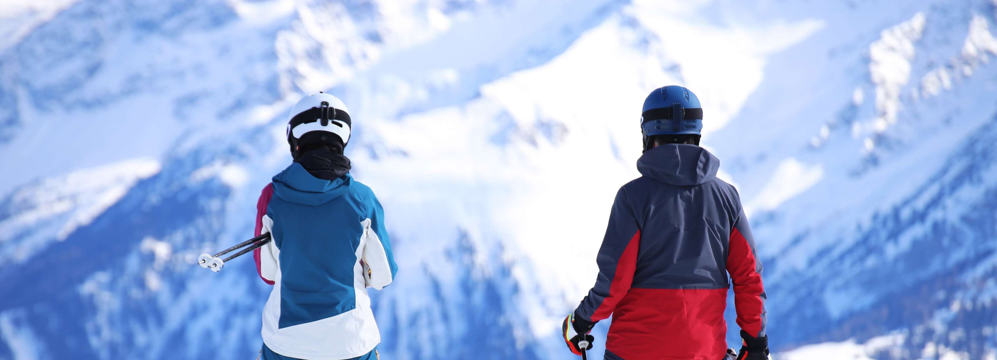 Zwei Skifahrer stehen auf einem Gipfel und schauen zu einem anderen Bergmassiv