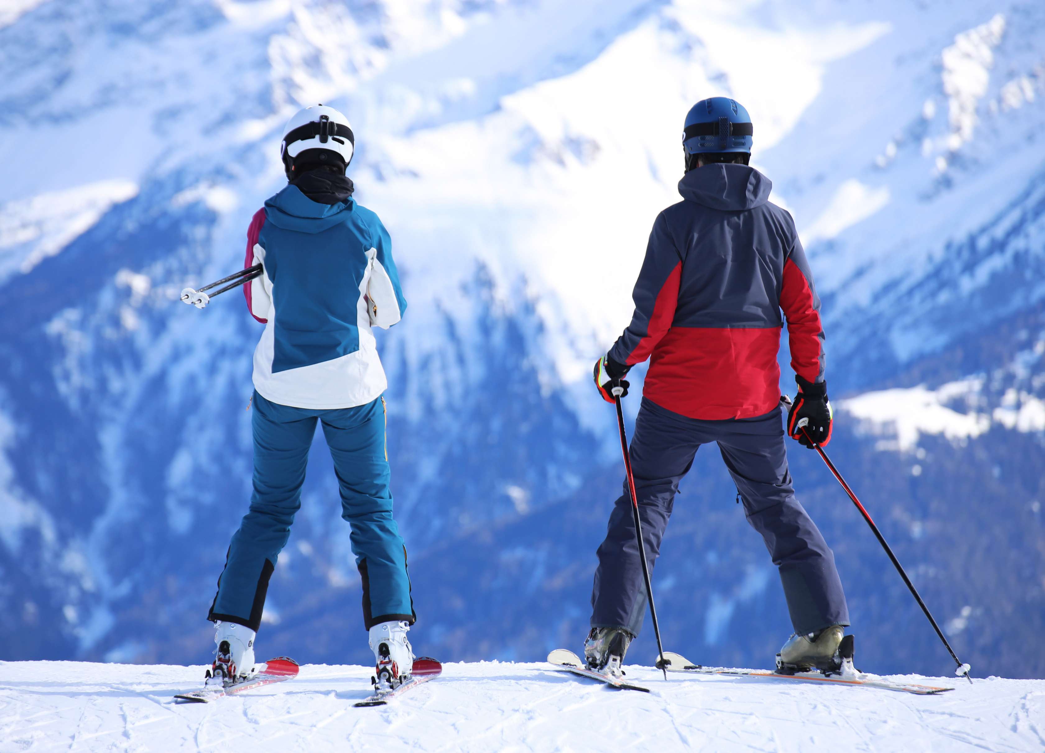 Allianz Unfallversicherung - Skiunfall: Zwei Skifahrer stehen auf einem Gipfel und schauen zu einem anderen Bergmassiv