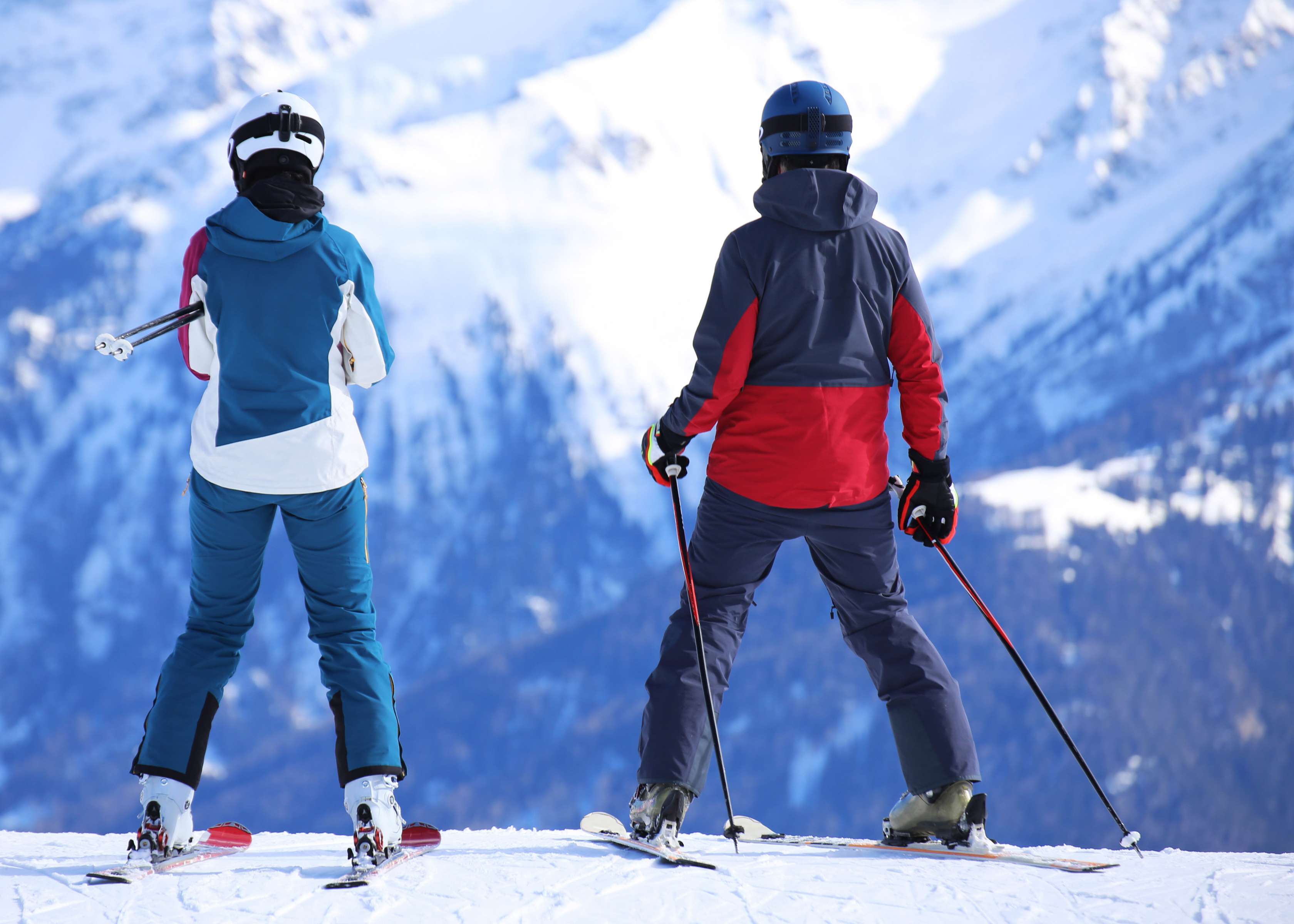 Allianz Unfallversicherung - Skiunfall: Zwei Skifahrer stehen auf einem Gipfel und schauen zu einem anderen Bergmassiv