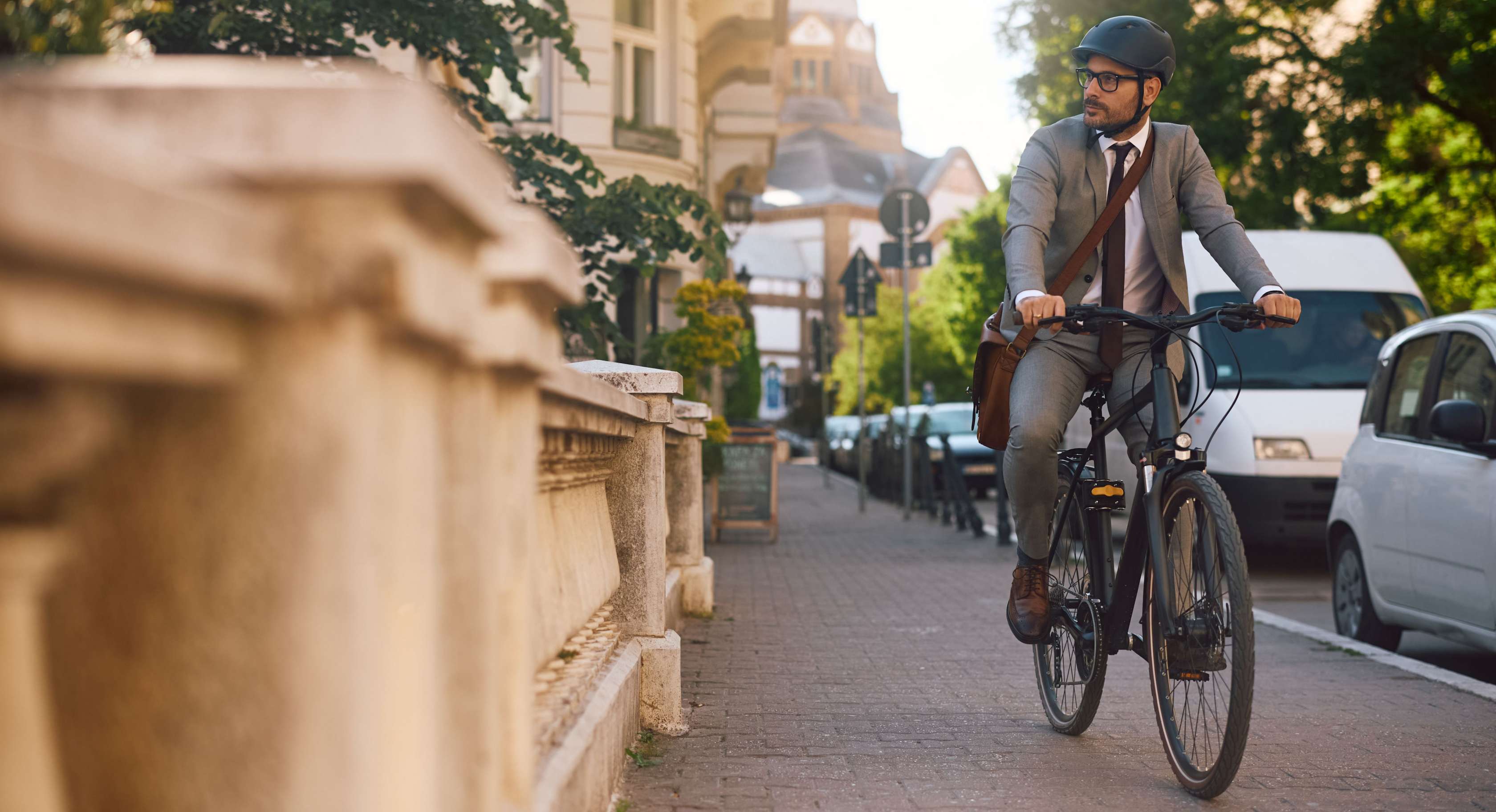 Wegeunfall: Mann im Anzug fährt mit einem Fahrrad auf dem Gehweg