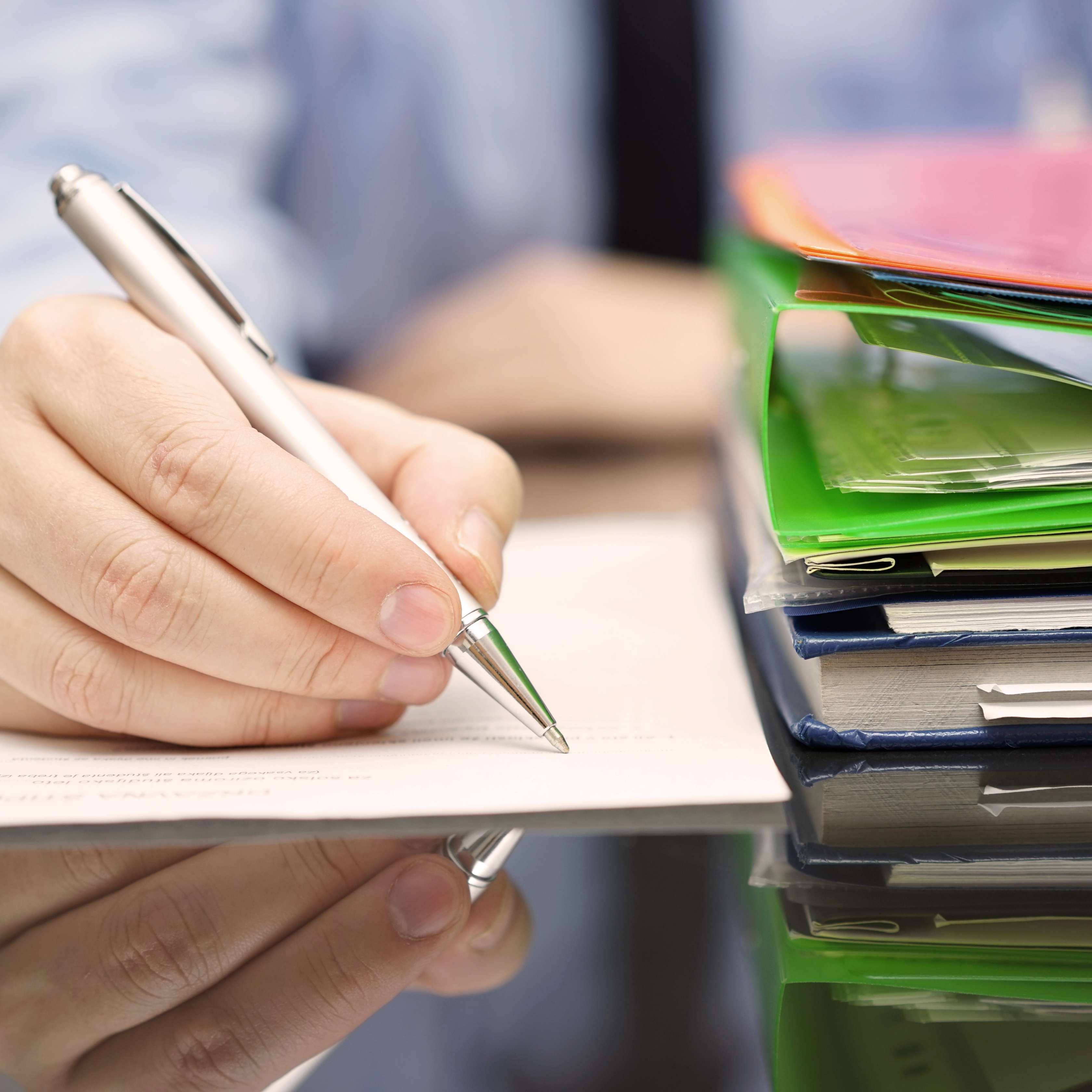 Allianz - Individuelle Anlagemöglichkeit: Hand mit Kugelschreiber auf Schreibtisch mit Akten